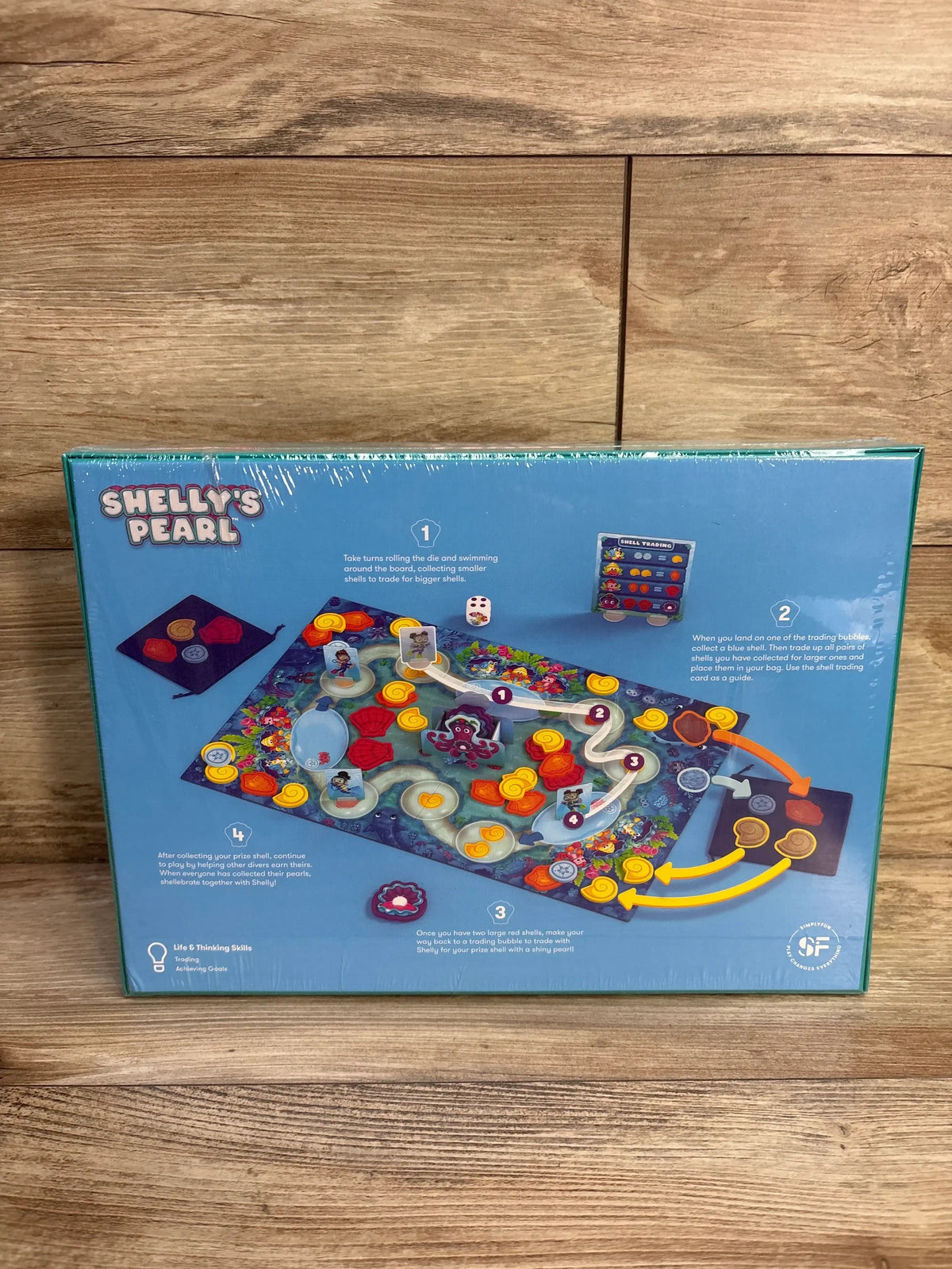 Back of Shelly’s Pearl board game box showing colorful game board illustration, pieces, and instructions on wood surface