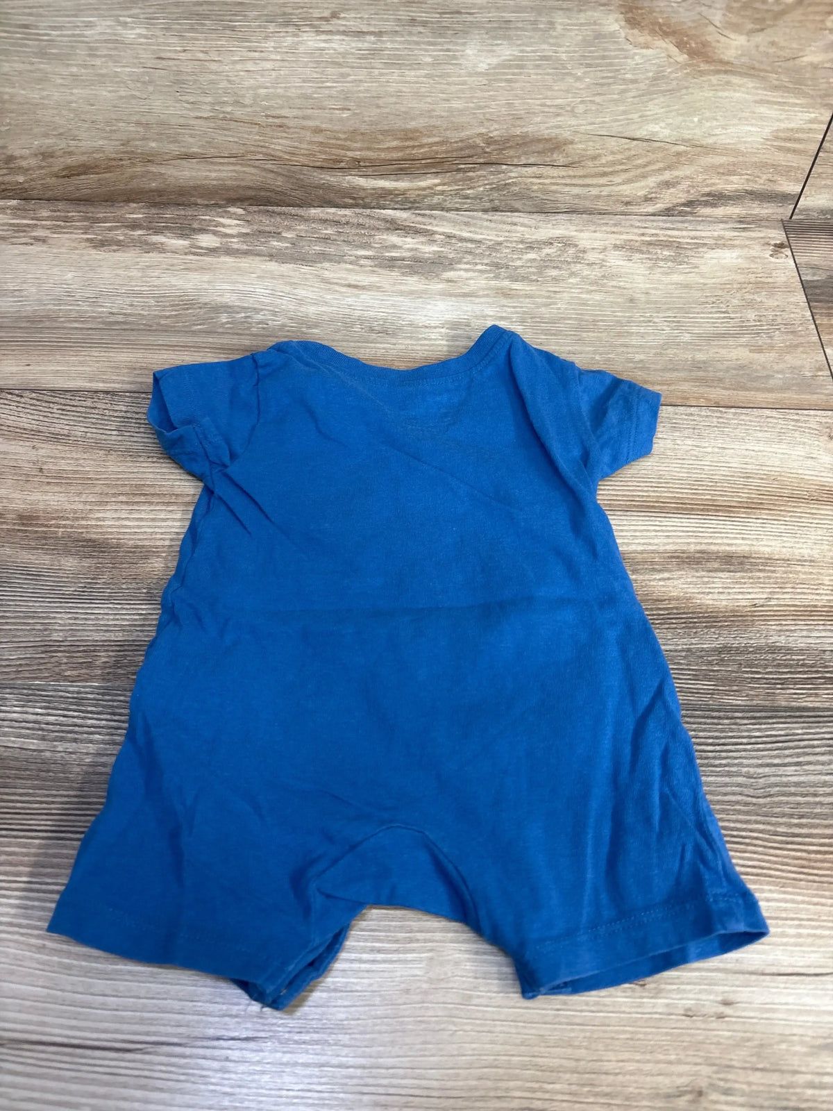 Front view of the blue Puma logo shortie romper in size 3-6m, showing short sleeves and legs on a wood-look floor