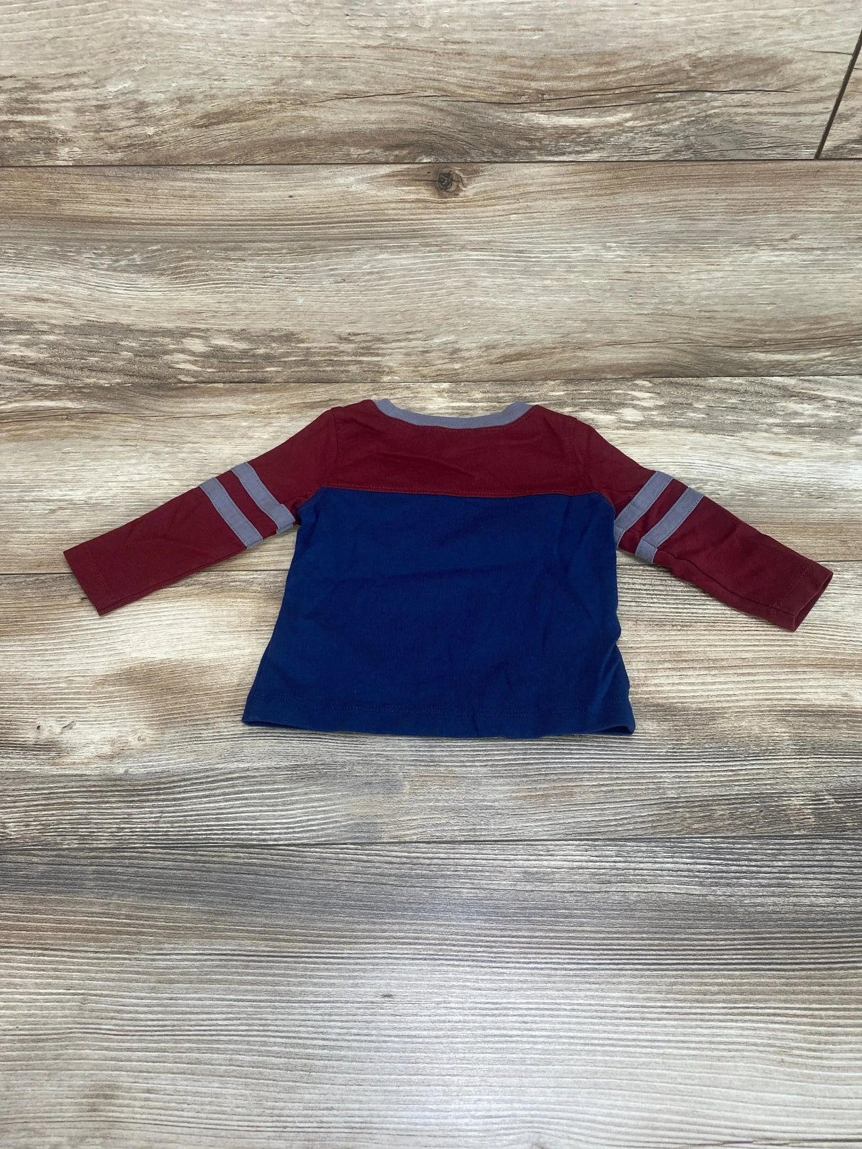 Back view of Old Navy color-block baby shirt with maroon sleeves and gray stripes over navy body on wood background