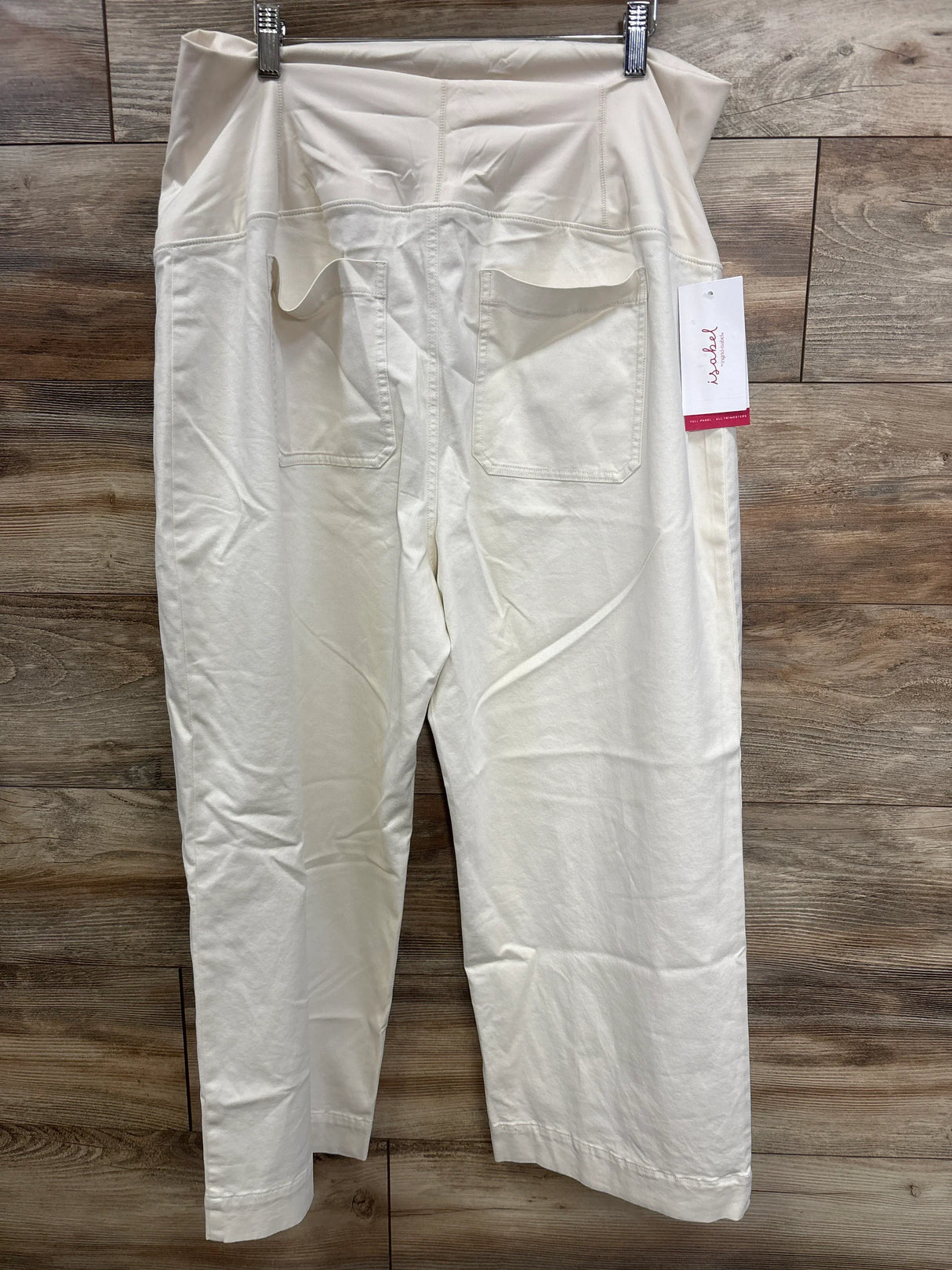 White maternity pants with back pockets displayed on a hanger against wood background