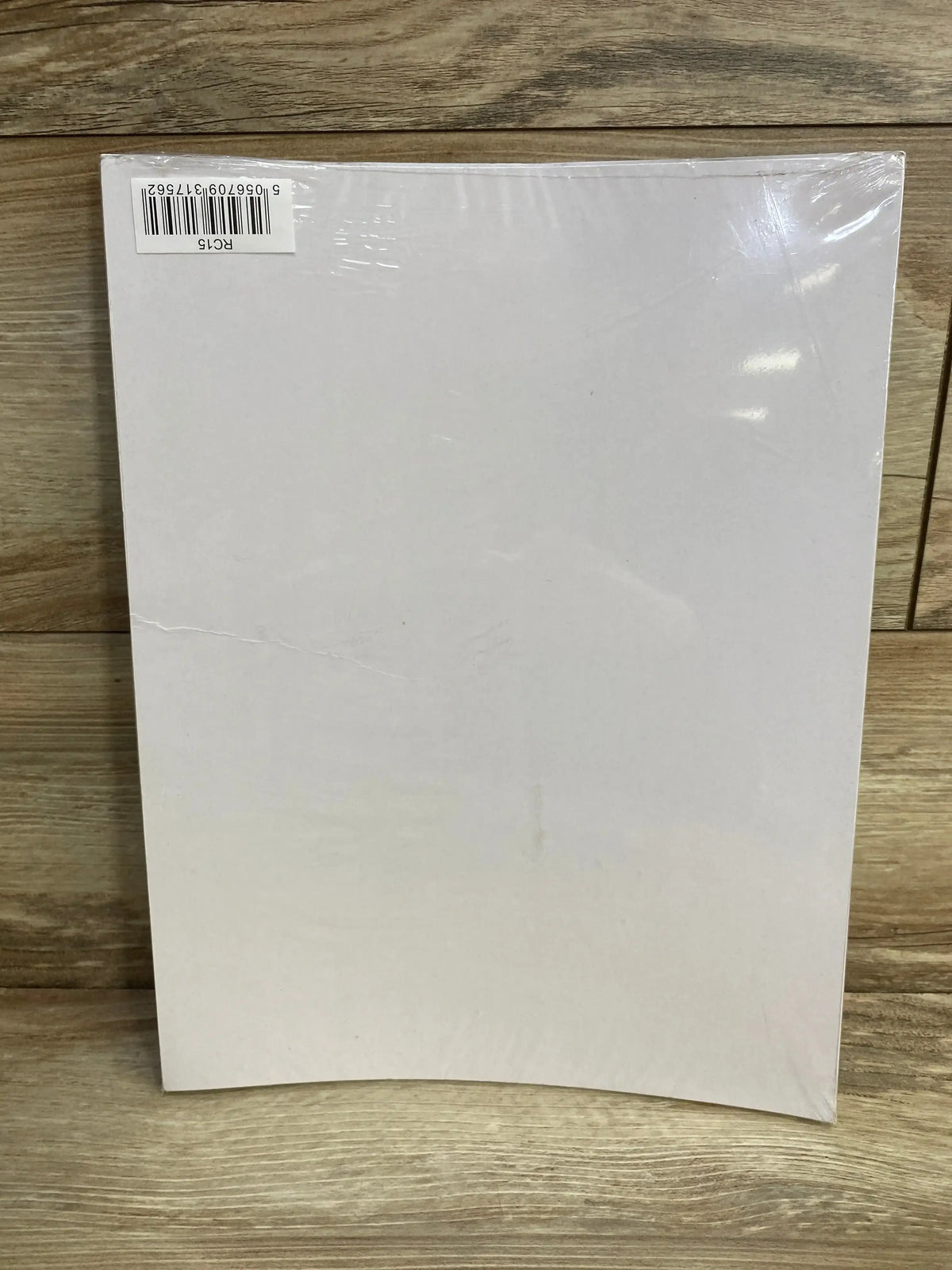 Rear view of reward chart showcasing blank white back with barcode sticker and plastic wrap on wood background