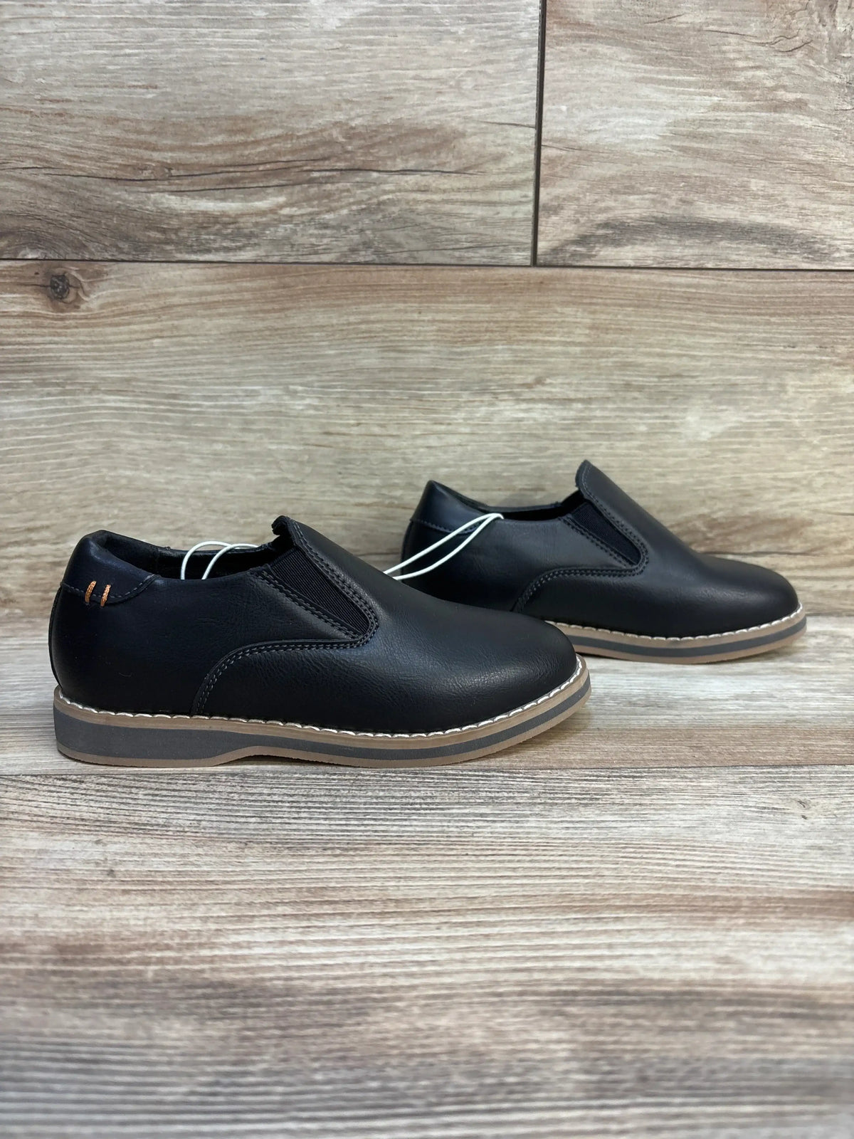 Side view of Cat and Jack Neal toddler loafers size 11C showing black slip-on upper with tan stitched sole on wood background