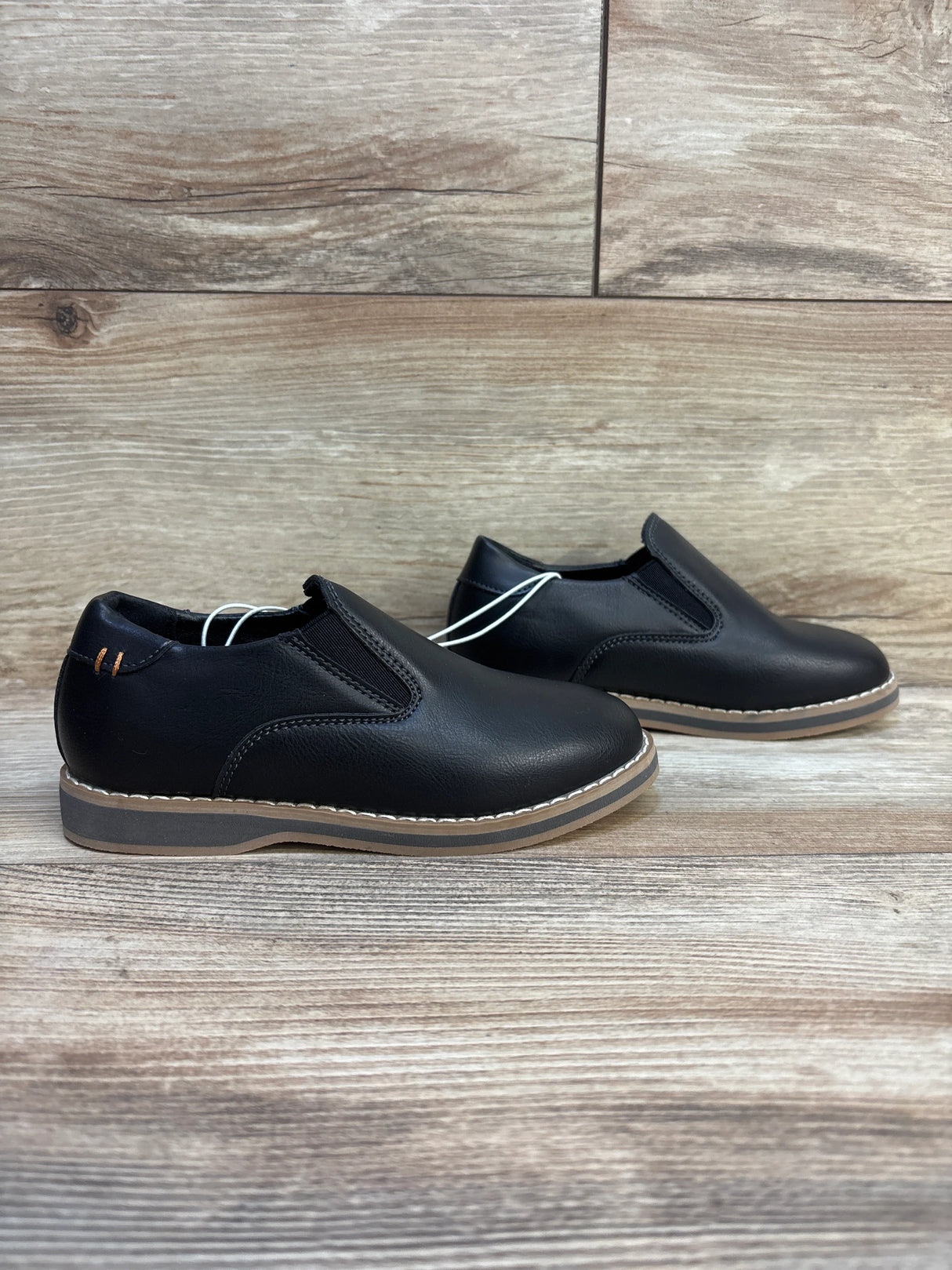 Side view of Cat and Jack Neal toddler loafers size 11C showing black slip-on upper with tan stitched sole on wood background