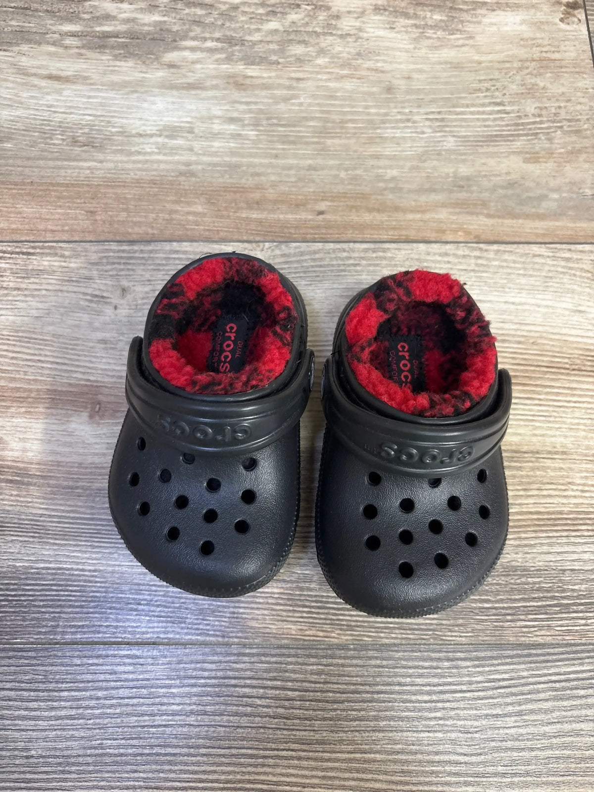 Top view of Crocs Classic Lined Buffalo Check toddler clogs size 4C showing black exterior and red fleece lining on wood floor