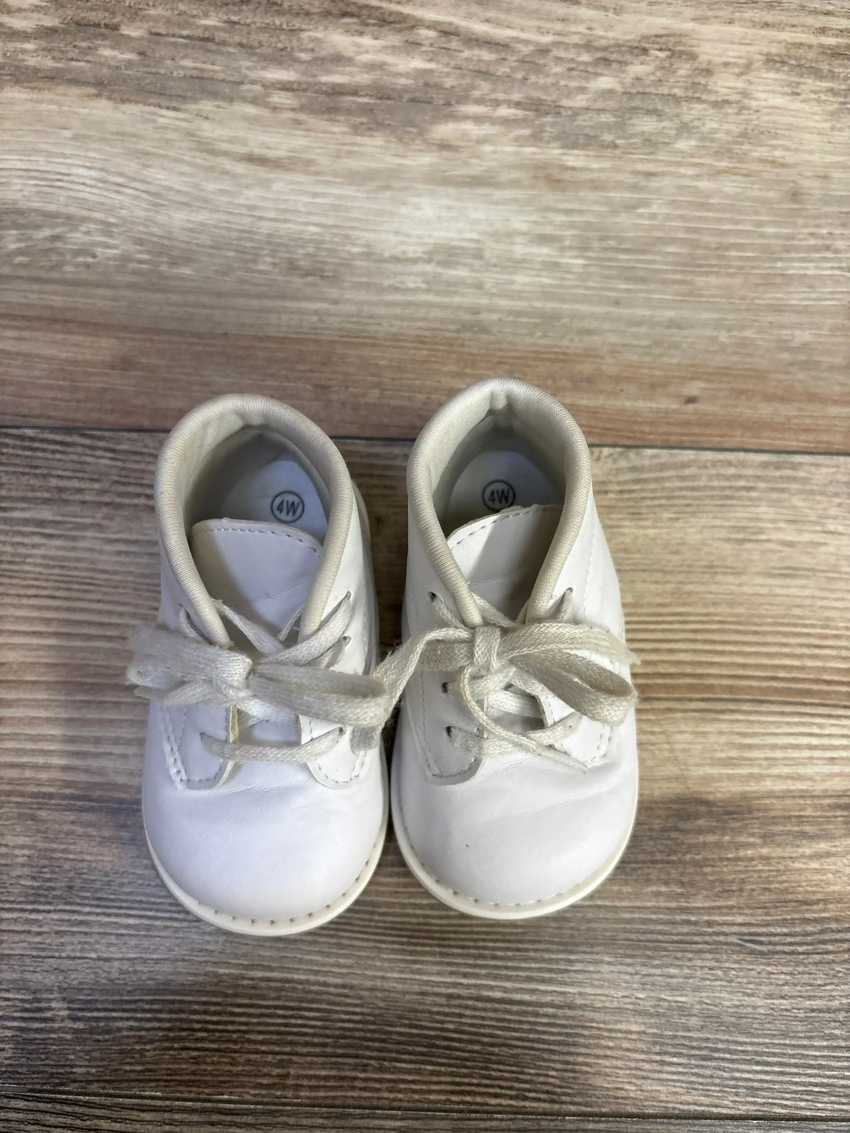 Top-down view of Teeny Toes first walker baby shoes showcasing tied laces and padded collar on light wood background