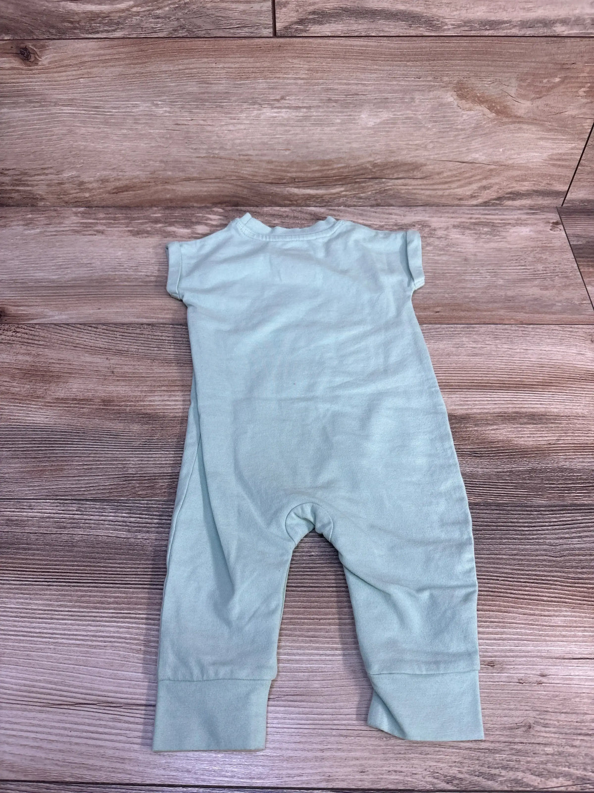 Back flat lay of Cat and Jack Mini Golfer romper in light green showing short sleeves and cuffed pant legs on wood background