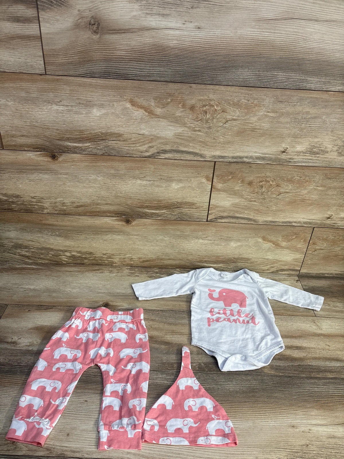Top view of PatPat three piece baby set showcasing white elephant bodysuit, elephant print pants and matching hat on wood flooring