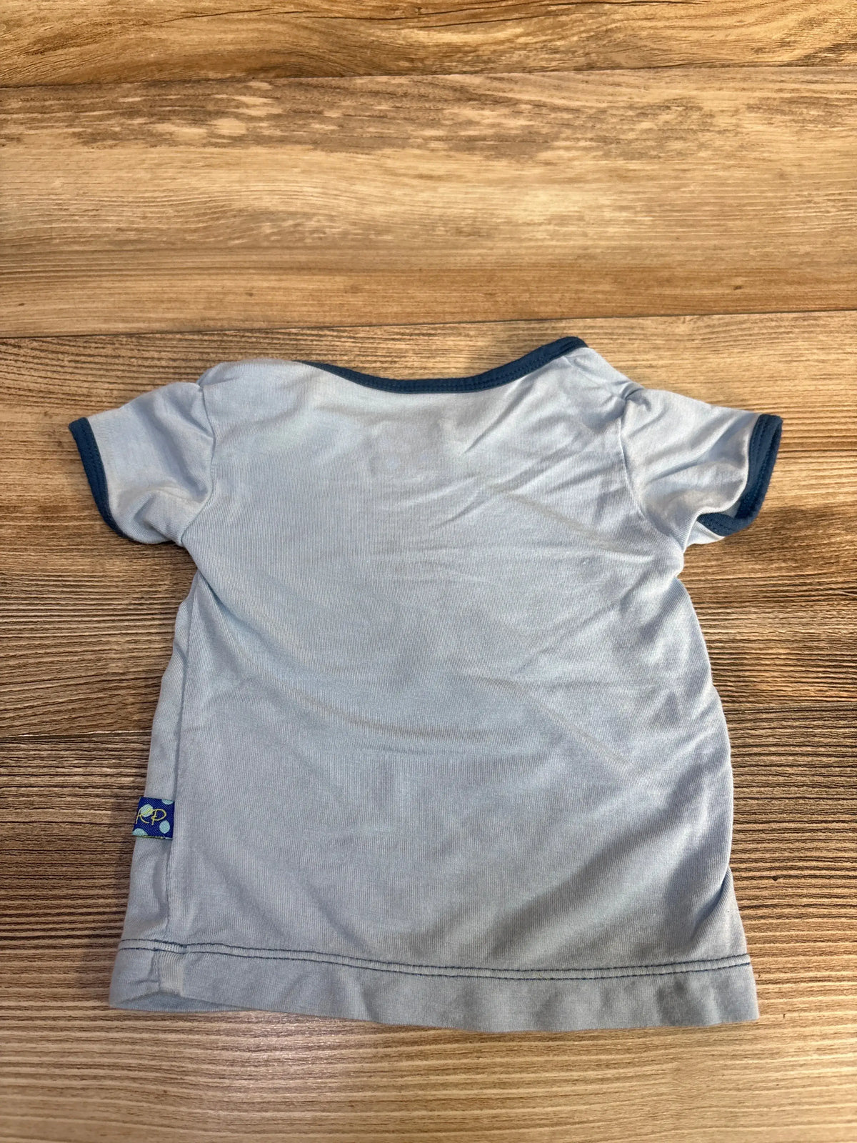 Back view of Kickee Pants bamboo treasure hunting shirt showcasing short sleeves and dark blue trim with a wood-grain background