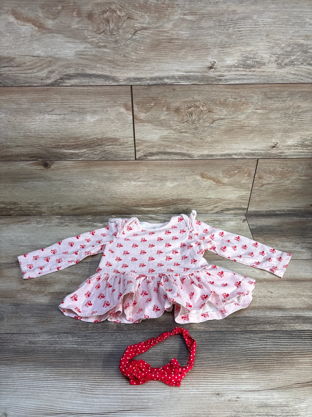 Flat lay of Disney Store Minnie Mouse two-piece set showcasing pink printed peplum top and red polka dot bow headband