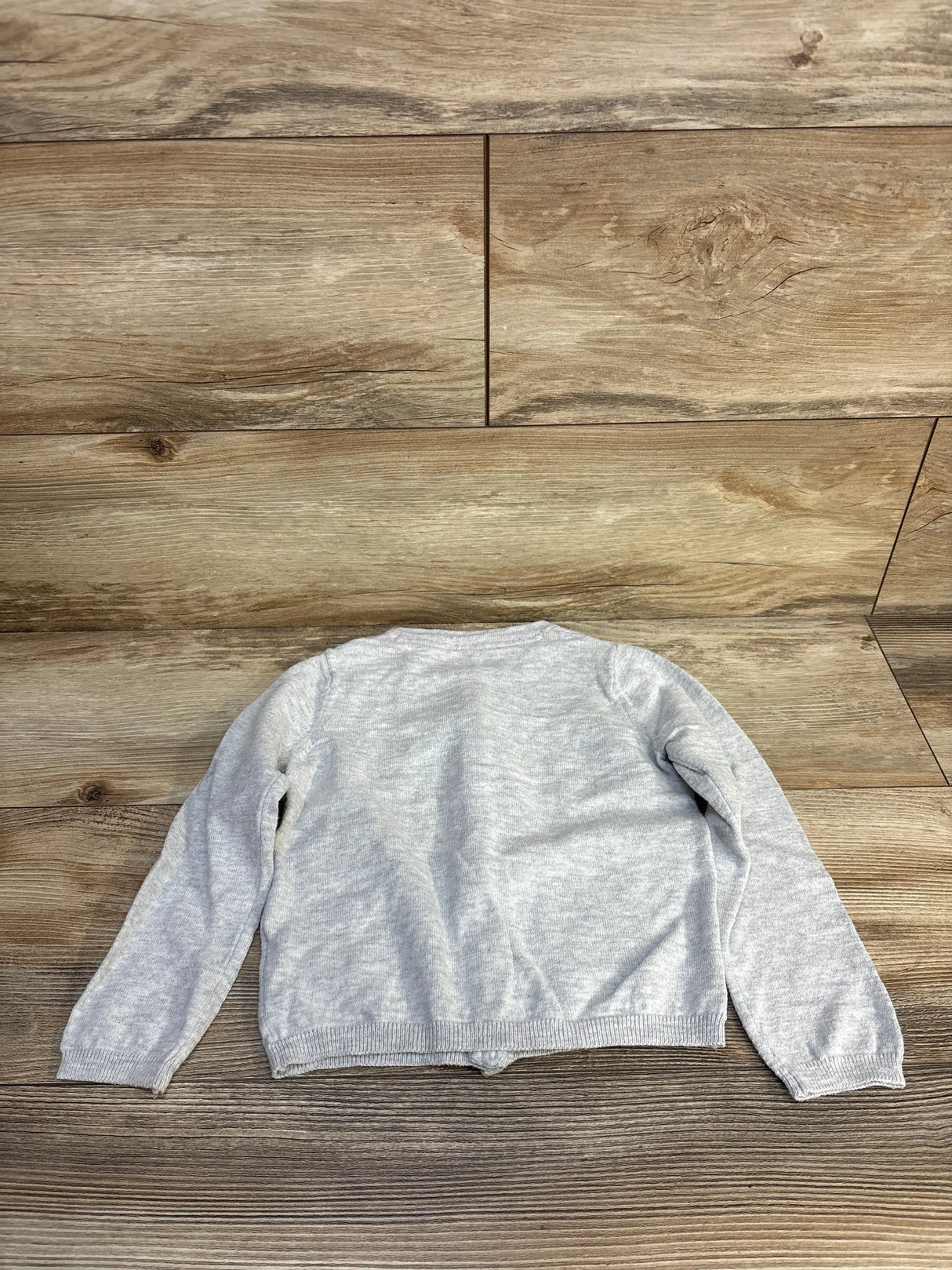 Light gray kids long sleeve sweater displayed flat on wood floor