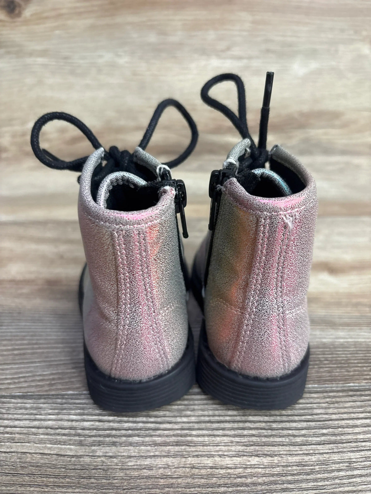 Rear view of metallic pink kids lace-up boots with zippers on wooden floor