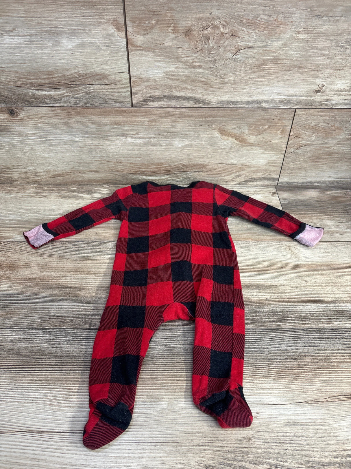 Red and black plaid baby sleeper with footies on wood background