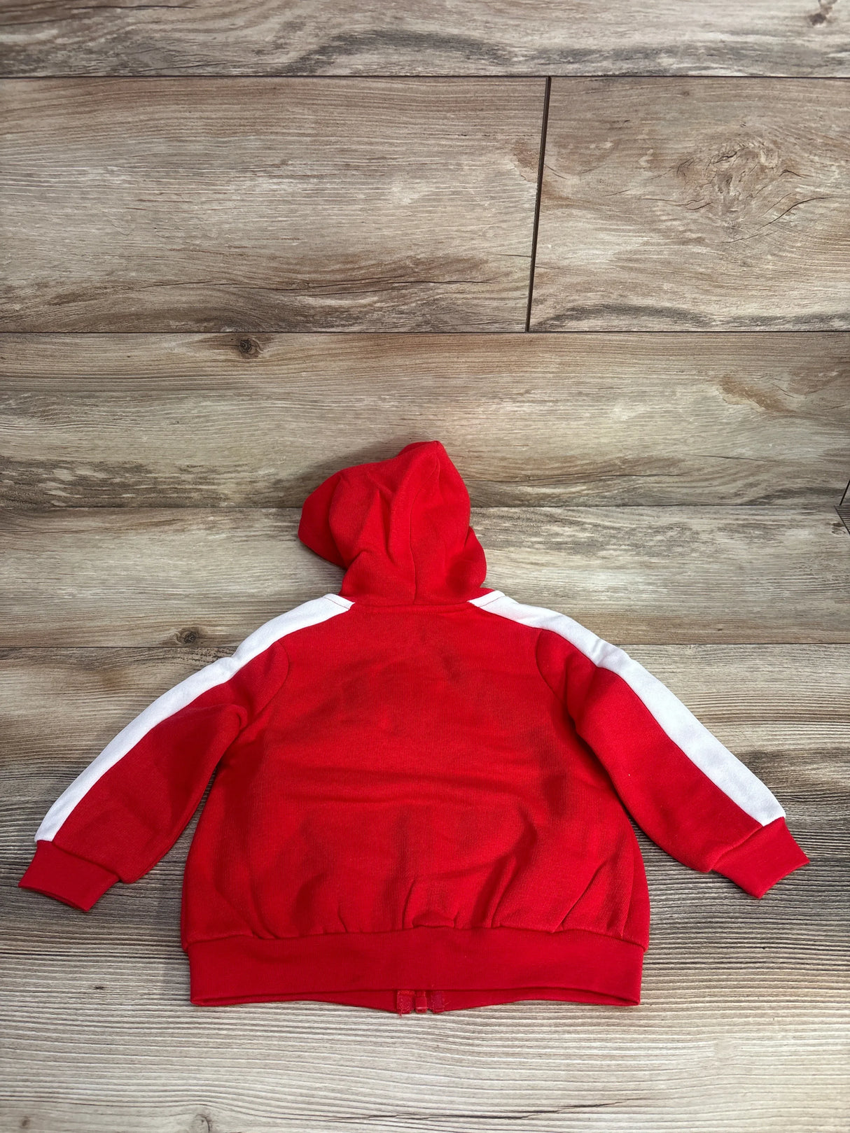 Back view of Okie Dokie full-zip red toddler hoodie showing white sleeve stripes and hood on wooden background