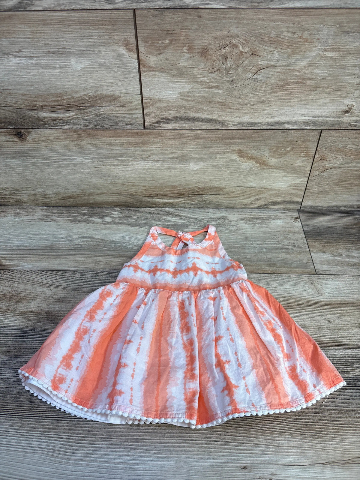 Front view of Max Studio peplum tank top showcasing its orange color and ruffled waist on a wood floor