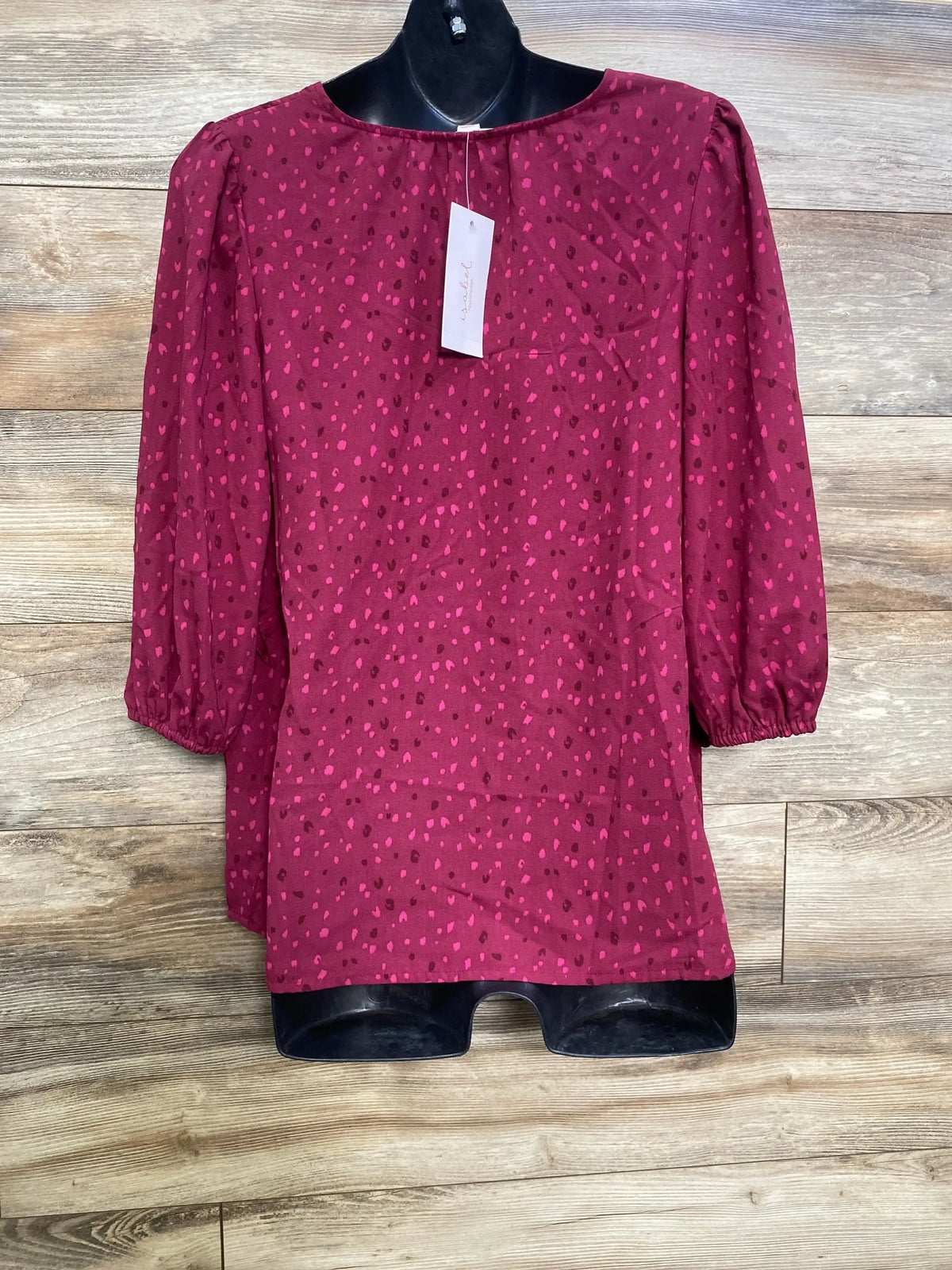 Front view of berry maternity top with ruffle waist, pink dot pattern and elastic three-quarter sleeves on black mannequin