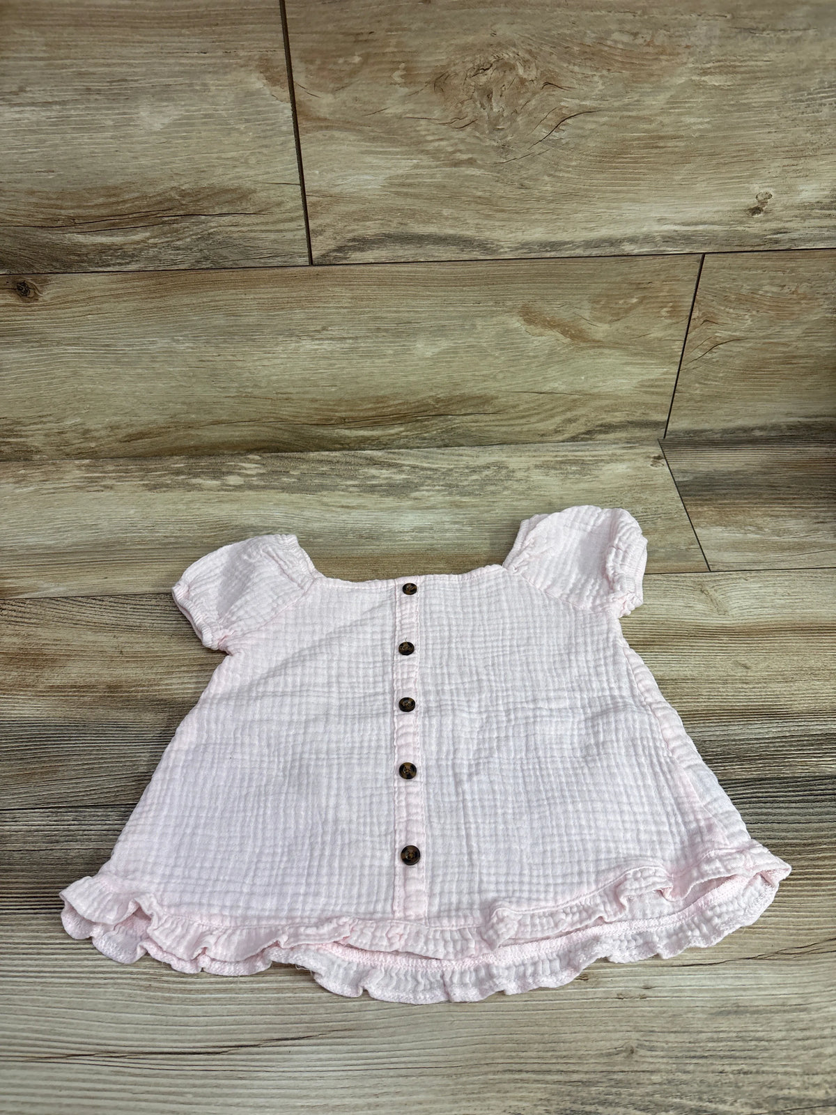 Pink Nannette gauze button-front top for kids size 5T on a wood-grain background