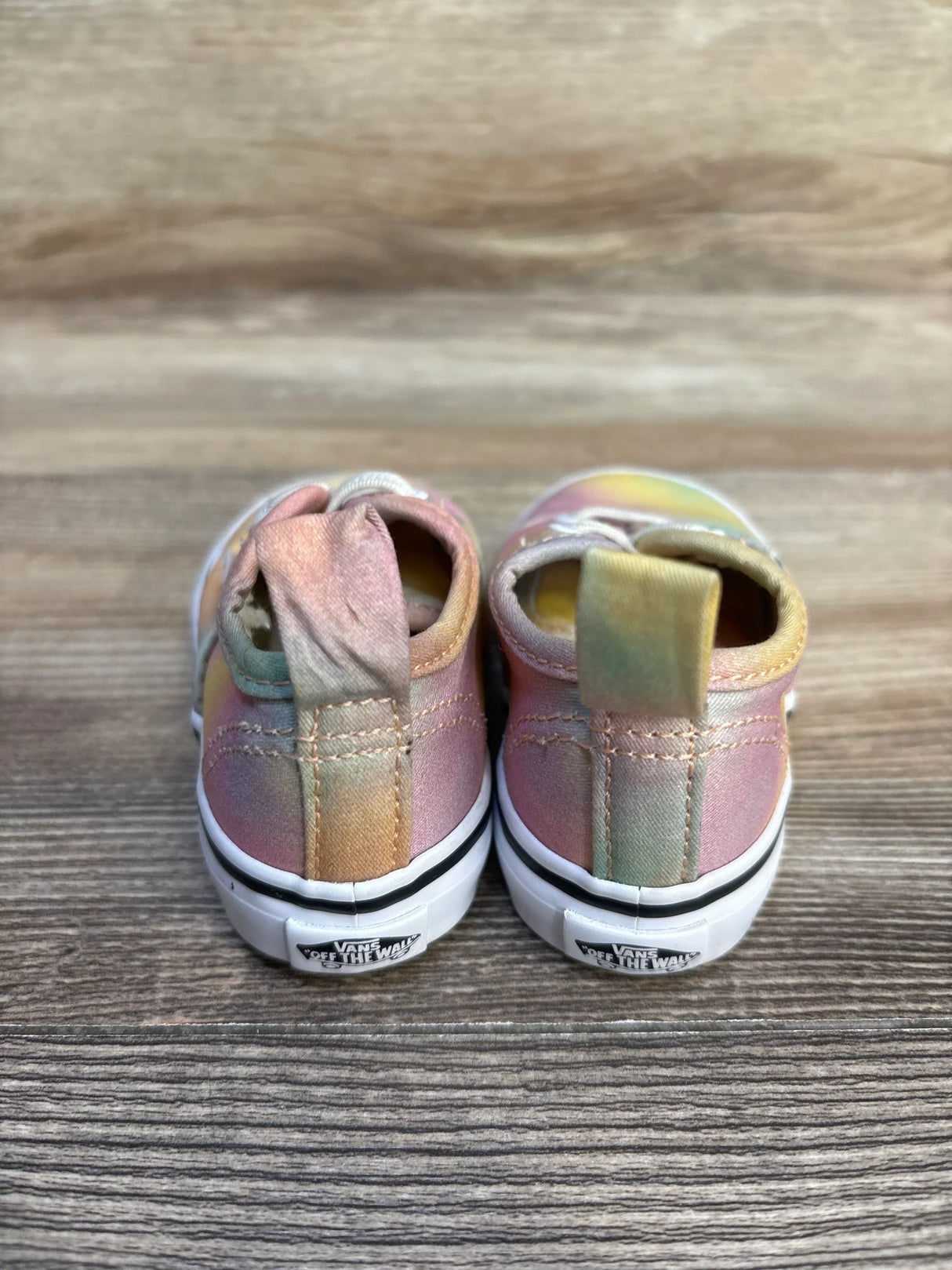 Back view of pastel tie-dye Vans toddler sneakers on wood background