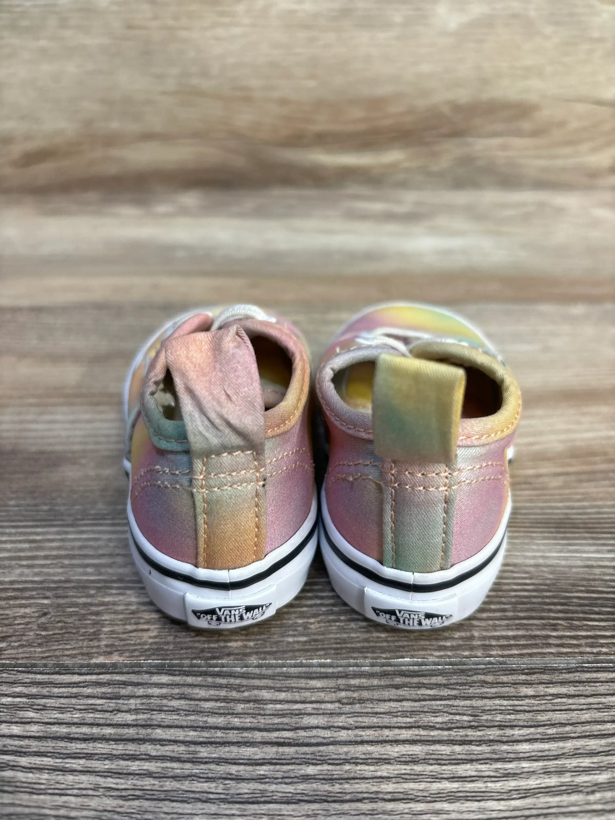 Back view of pastel tie-dye Vans toddler sneakers on wood background