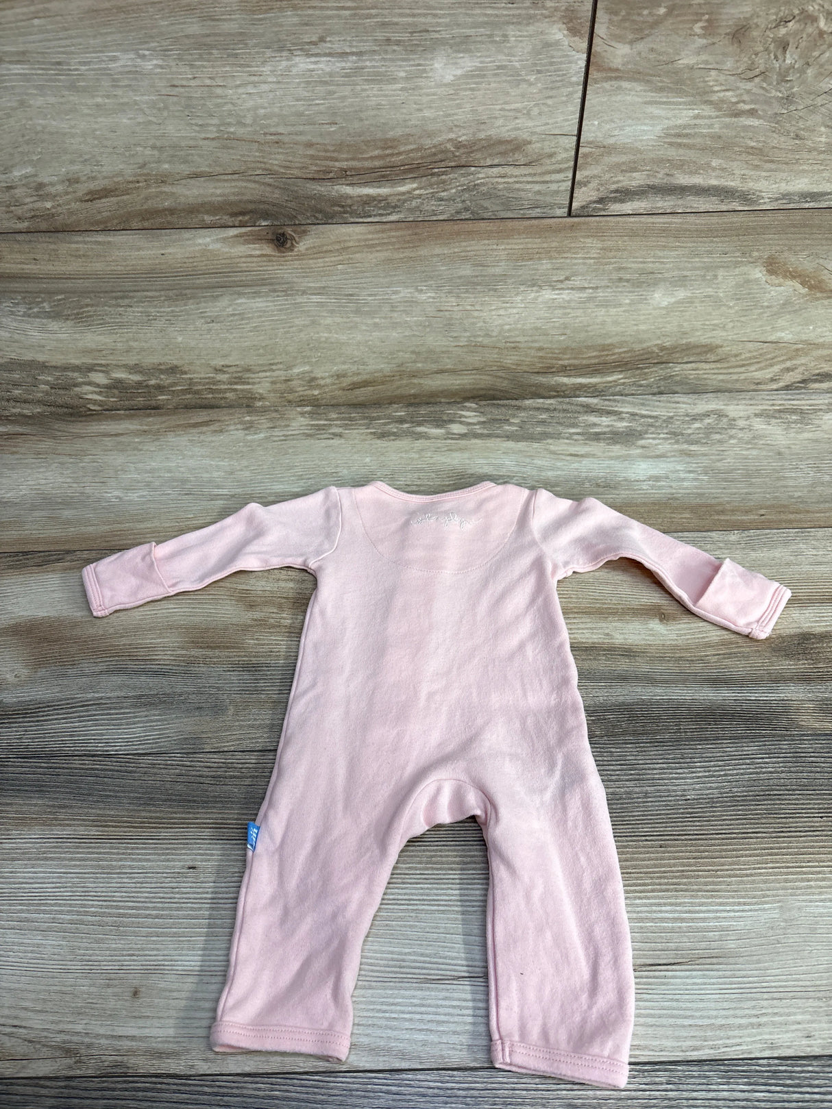 Soft pink long-sleeve baby onesie laid flat on wooden floor, children's clothing resale