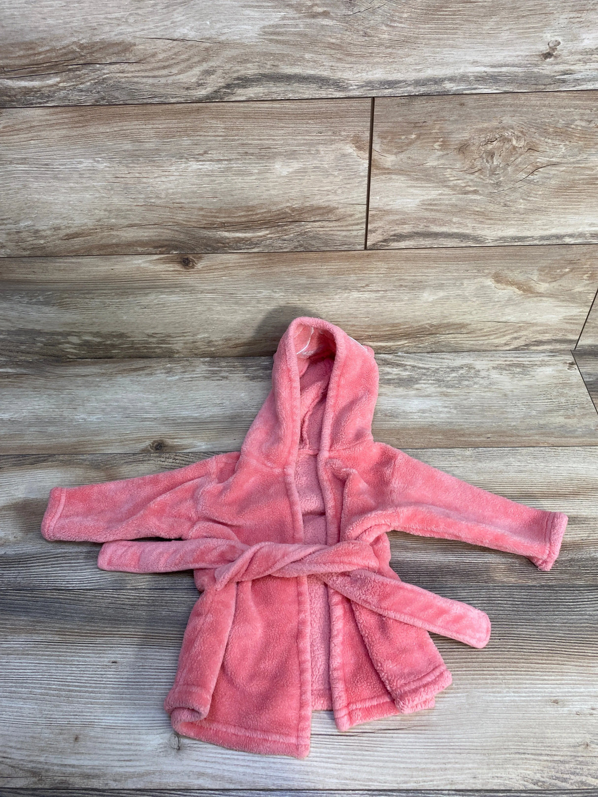 Pink hooded fleece robe for kids on wooden floor, cozy children's bathrobe with belt