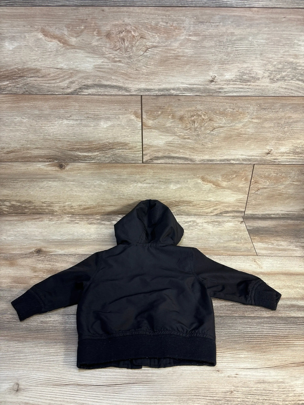 Black kids hooded jacket laid flat on wood floor, cozy outerwear for toddlers