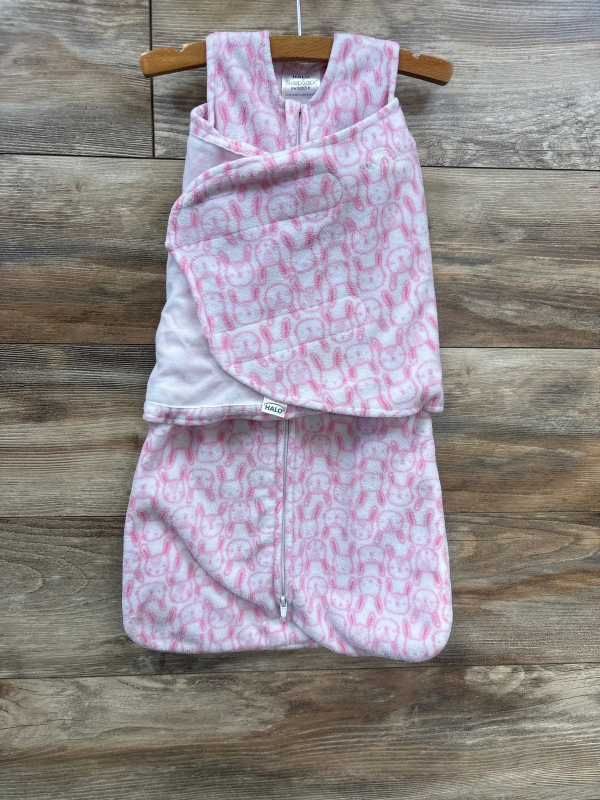 Pink and white infant swaddle sleep sack with bunny pattern on wooden background