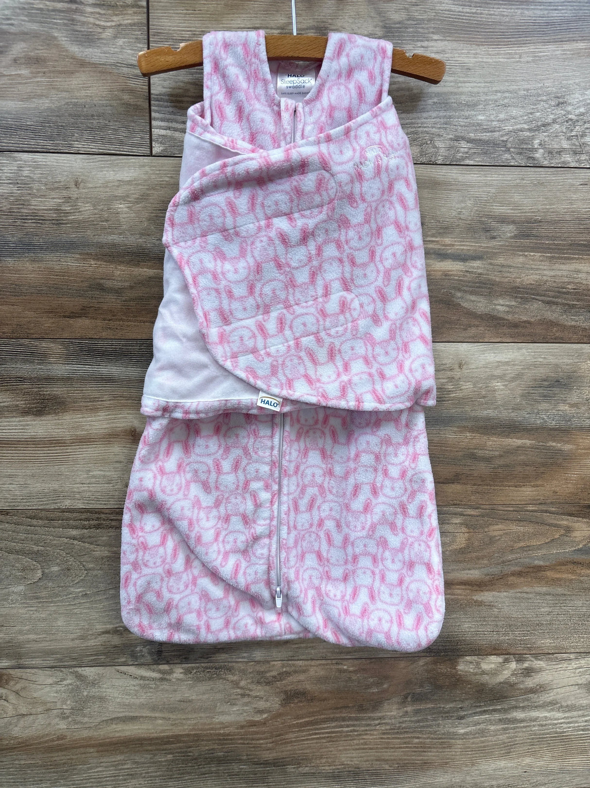 Pink and white infant swaddle sleep sack with bunny pattern on wooden background