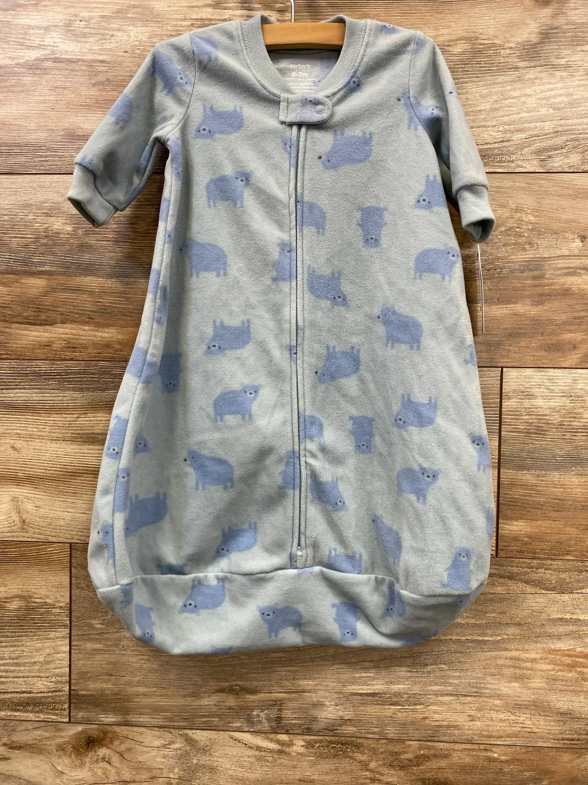 Front view of Carter's bear-print newborn sleep sack (0-3M) with light-blue fleece, zipper and cuffed sleeves on wood