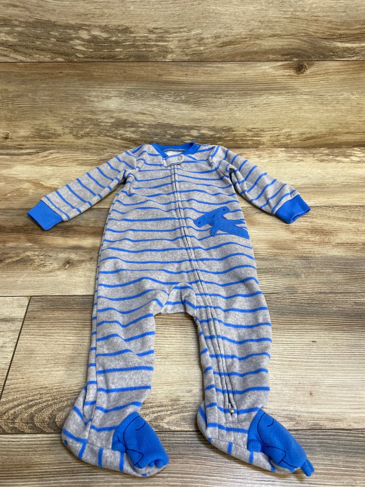 Flat lay of grey and blue striped hammerhead shark sleeper with footed feet and front zipper on wood floor