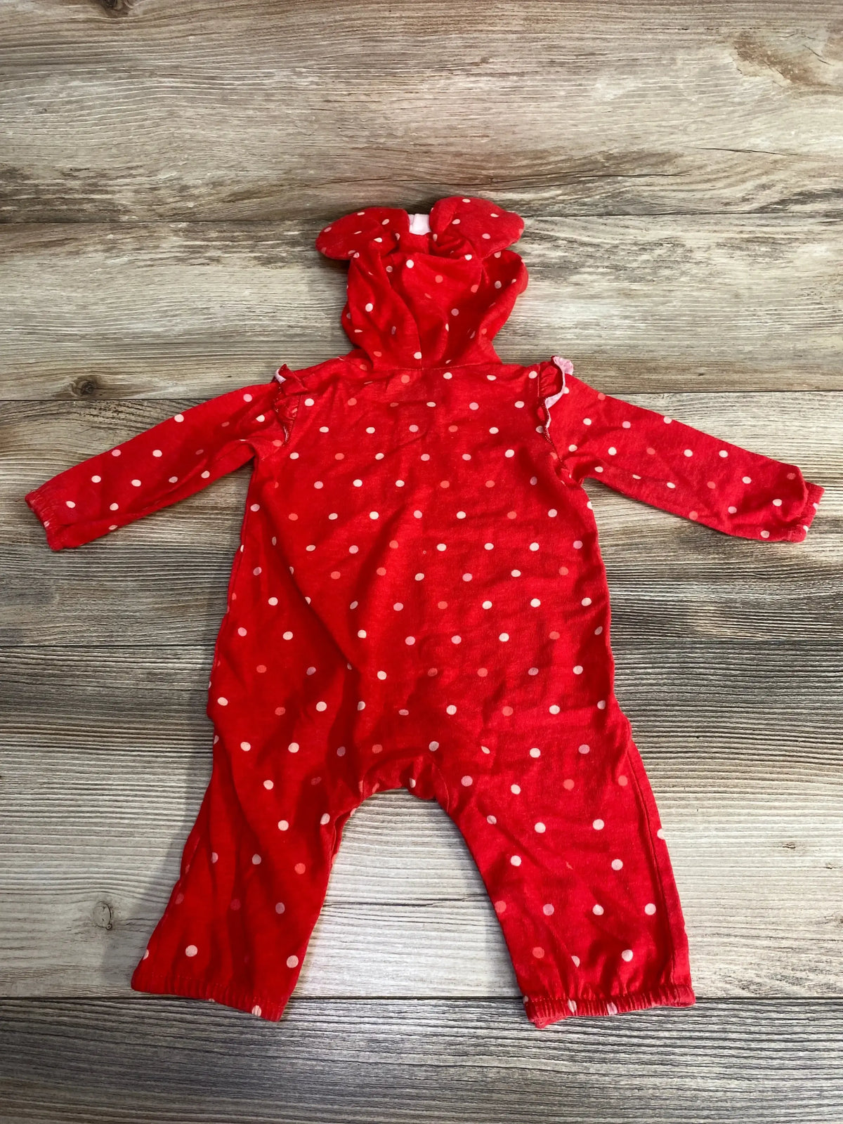 Flat lay of Disney Baby Minnie Mouse red polka dot hooded coverall 3M showing hood with ears and full-length legs on wood background