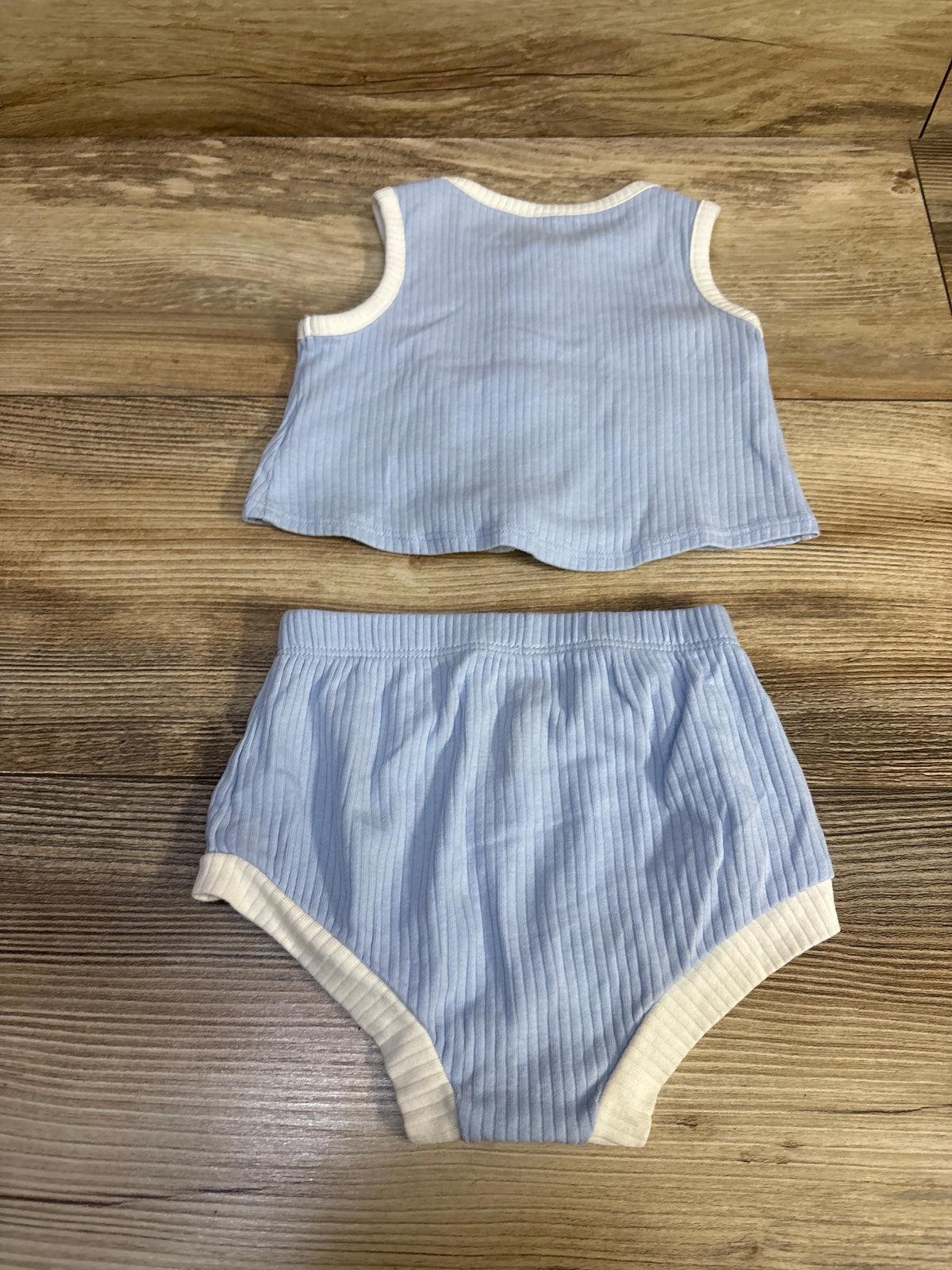 Flat lay of Cat & Jack 2-piece blue ribbed tank top and bloomers showcasing white trim and elastic waist on wood background