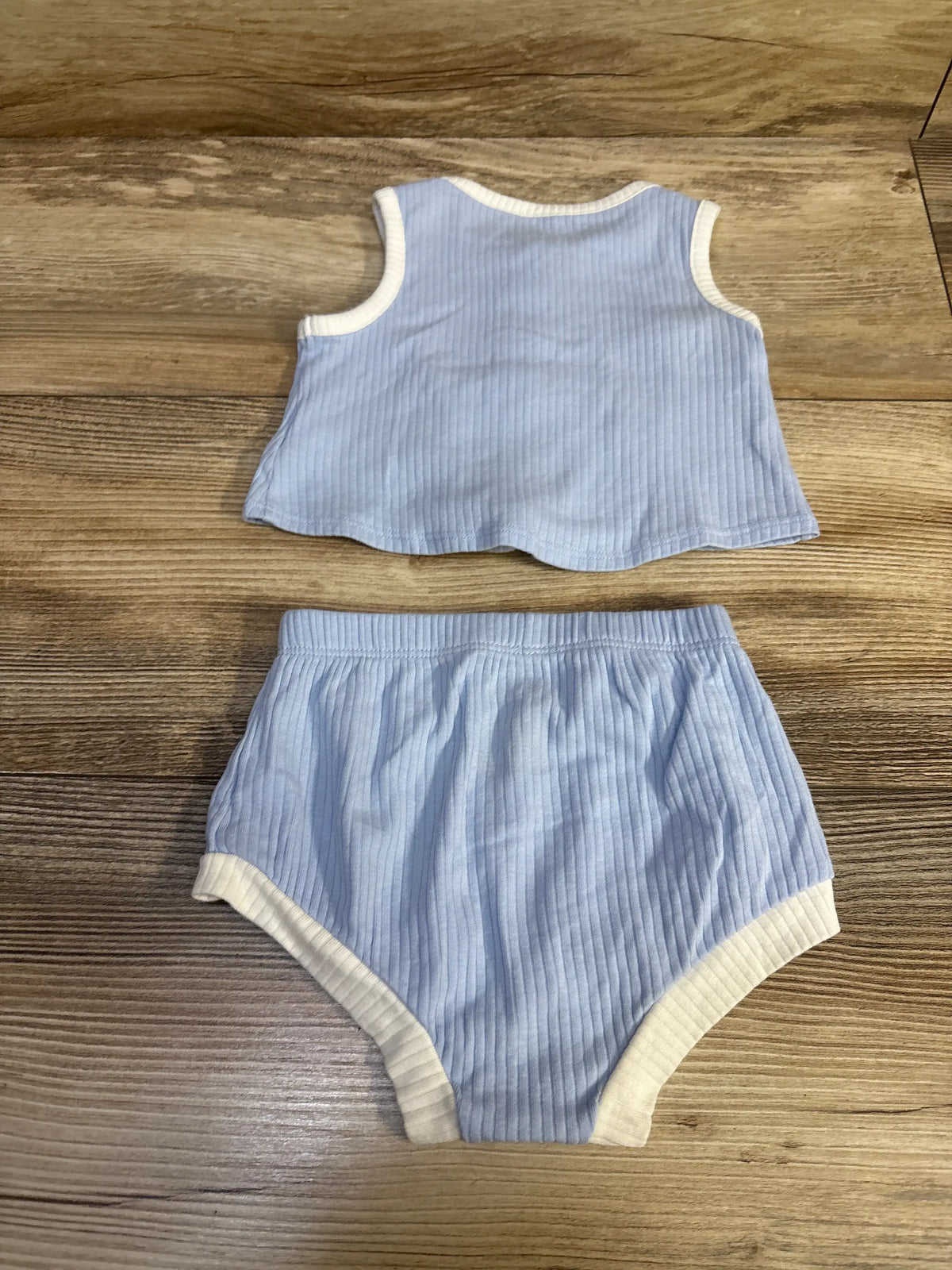 Flat lay of Cat & Jack 2-piece blue ribbed tank top and bloomers showcasing white trim and elastic waist on wood background