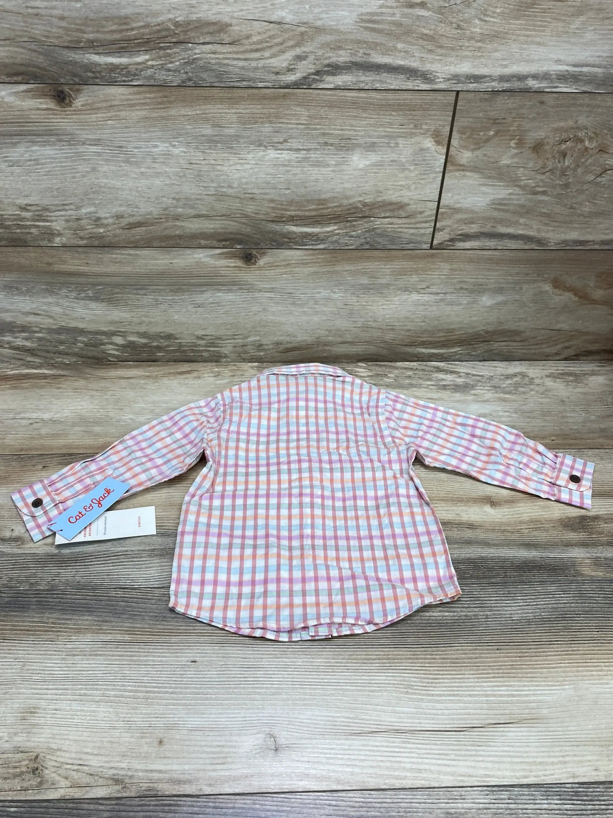 Back of Cat & Jack toddler plaid button-up shirt, pink/white/blue, sleeves with button cuffs, size 18m, on wood background