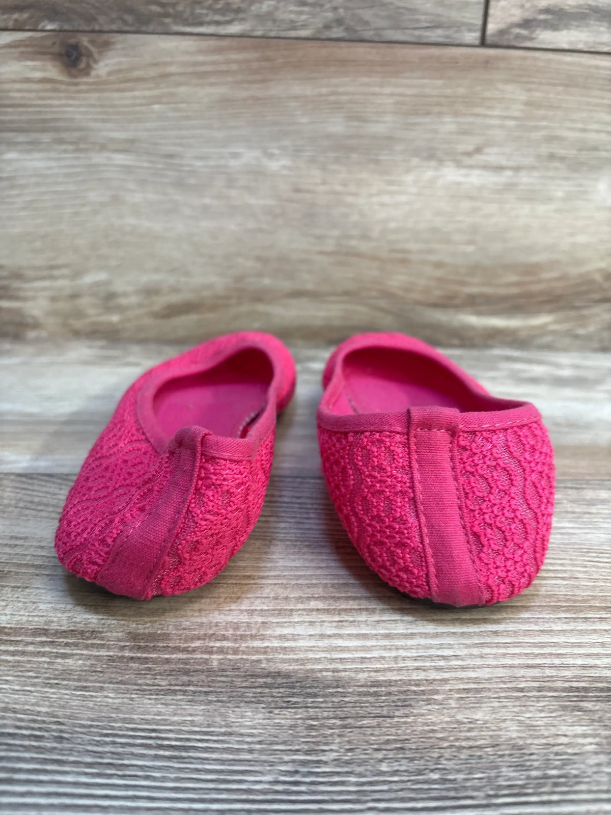 Pink lace toddler ballet flats on wooden floor, gently used kids shoes