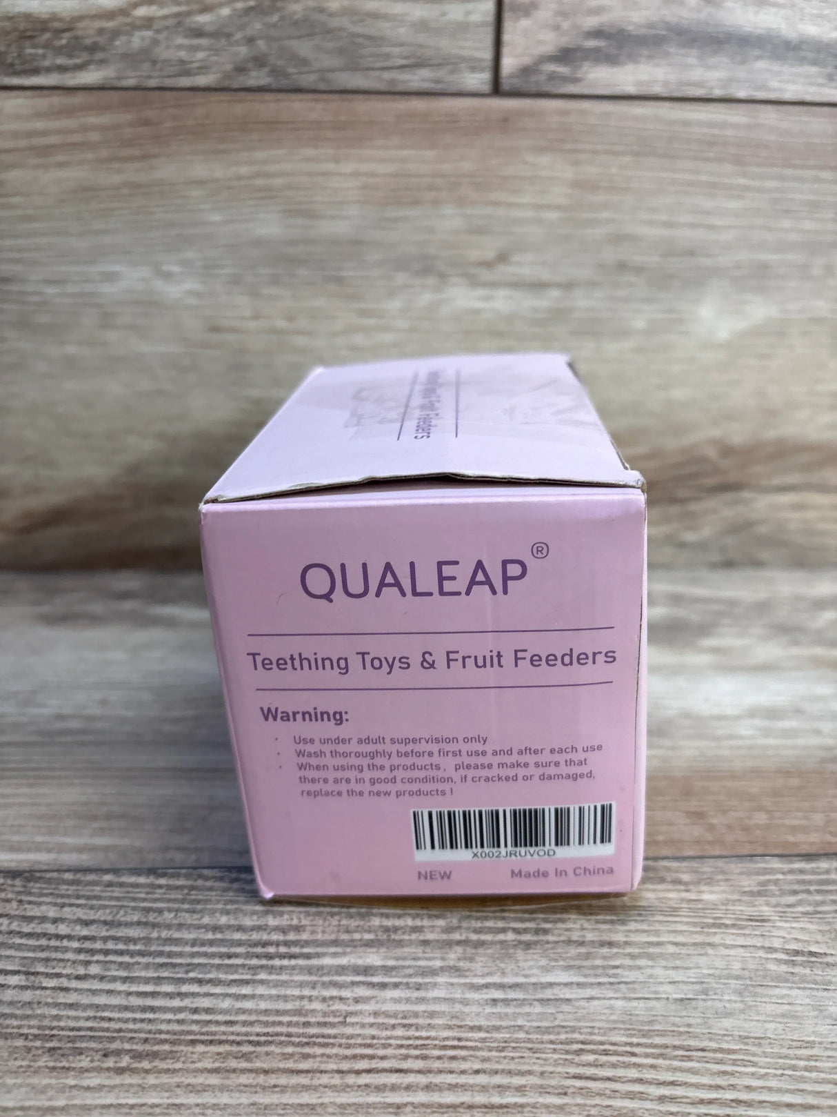Qualeap teething toys and fruit feeders box on wood background, baby product packaging