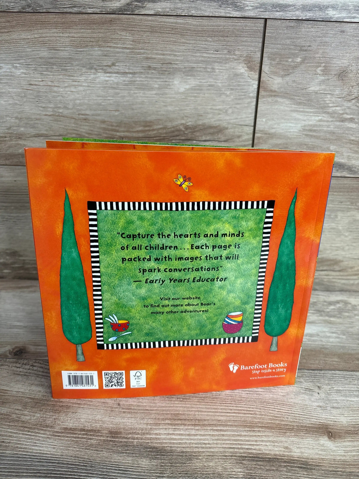 Back cover of Bear's Busy Family paperback showing review quote 'Capture the hearts' and Barefoot Books logo on orange