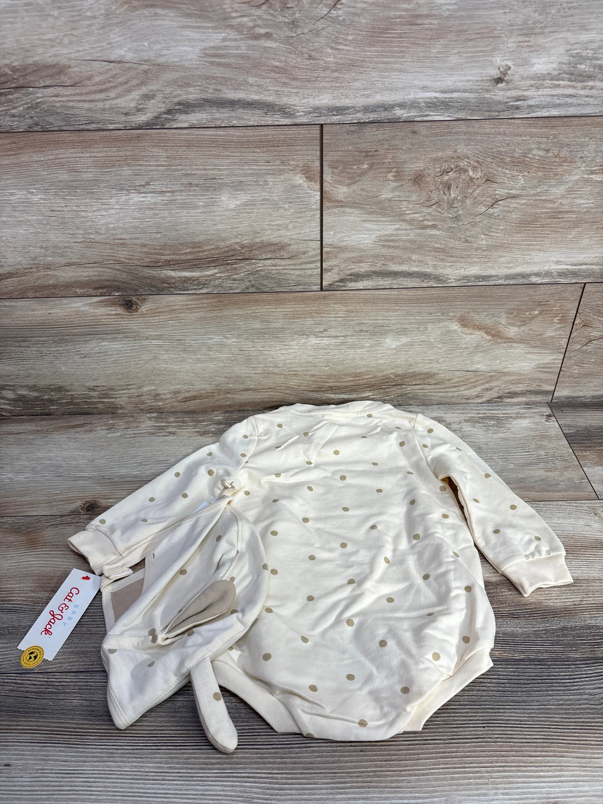 Cream-colored baby bodysuit with long sleeves and beige polka dots, paired with matching bunny ear hat