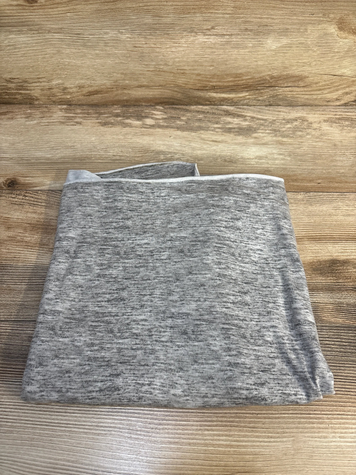 Folded gray heather maternity top on wood floor, soft fabric, resale kids & maternity clothing