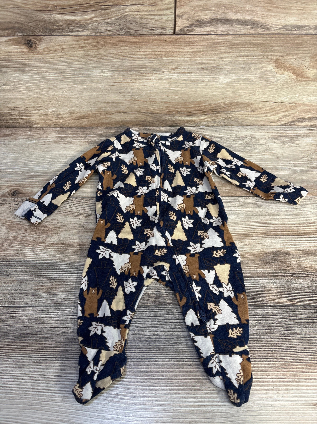 Baby sleeper with bear, tree, and leaf print on wood background