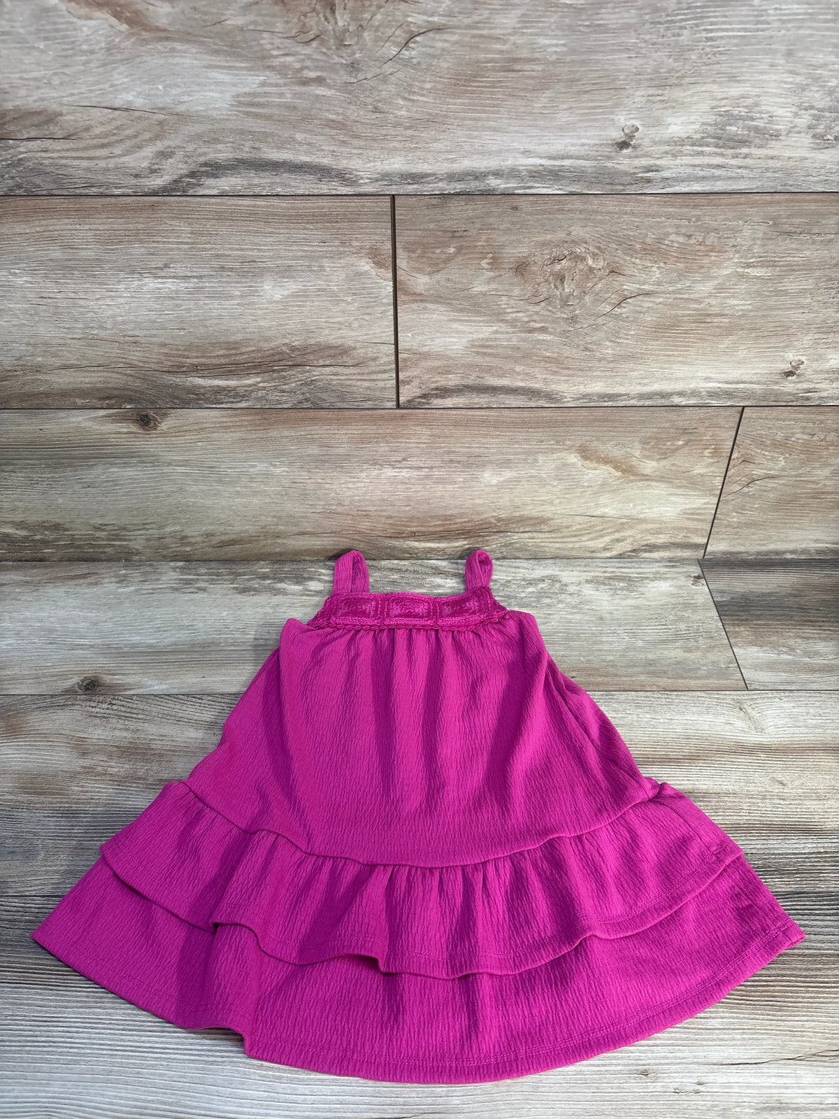 Front view of hot pink dropped waist knit tank dress showcasing square neckline and tiered skirt on wood flooring