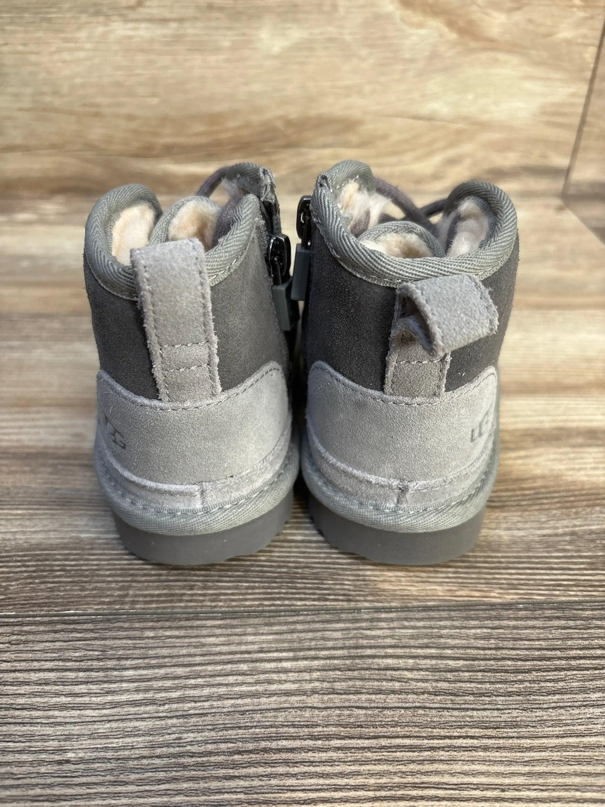 Gray toddler suede boots with fleece lining, side zippers, and textured soles on wood floor