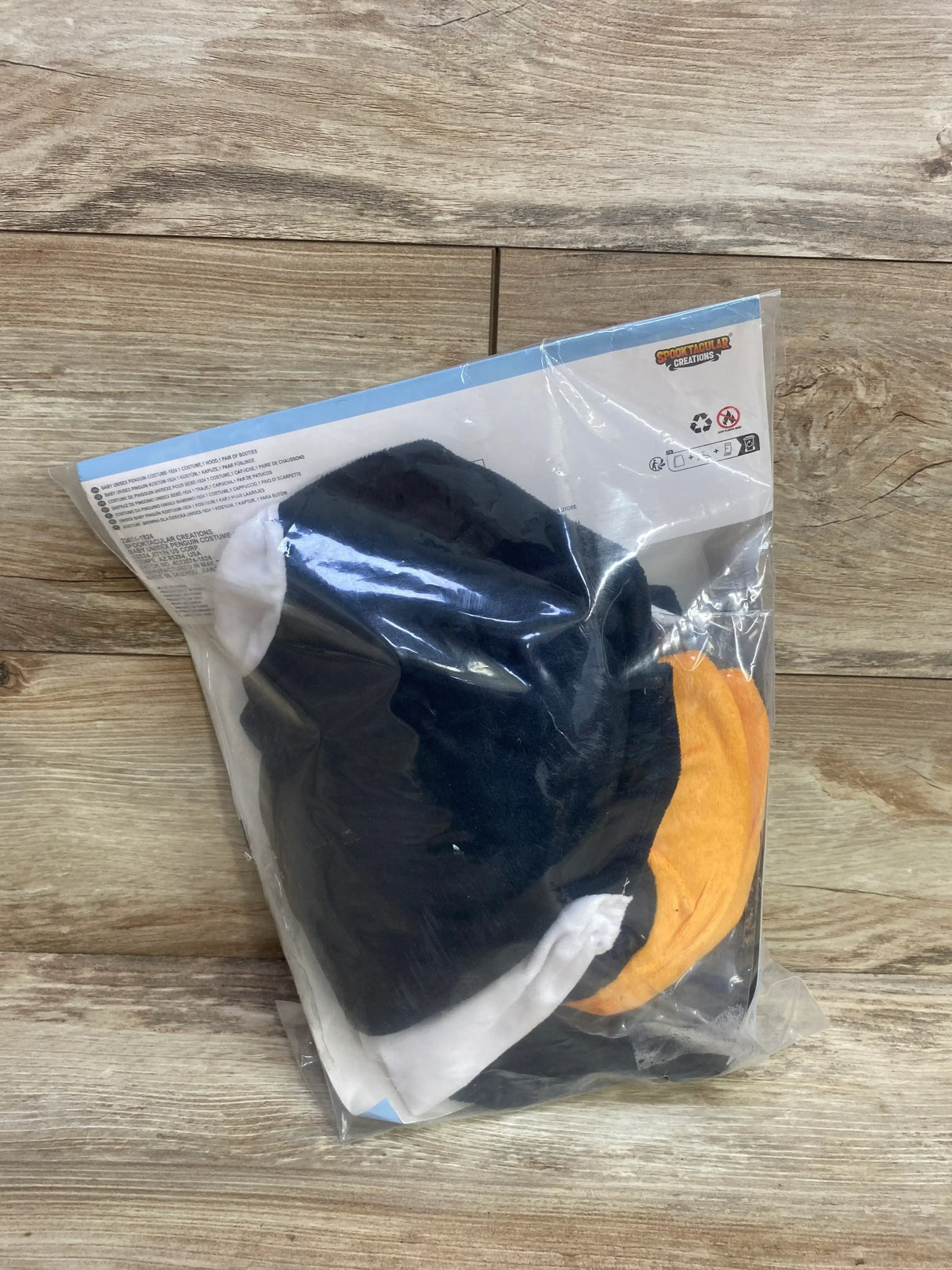 Baby penguin costume in black, white, and orange, packaged for resale
