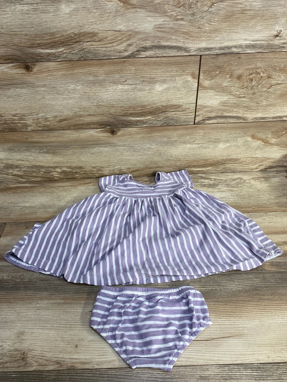 Top view of purple and white striped toddler dress and matching bloomers showing flared skirt and elastic waist on wood