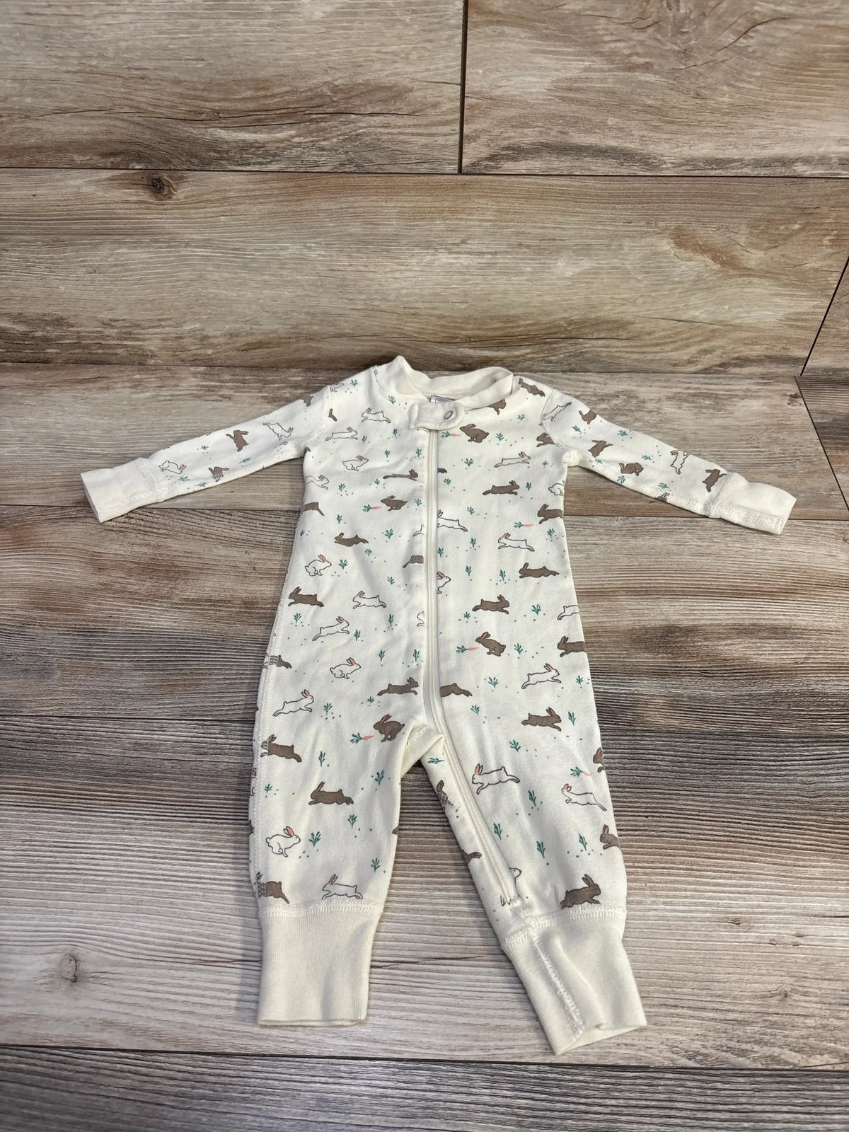 Front view of Hanna Andersson pale yellow bunny footless sleeper with allover bunny print on wood-grain background