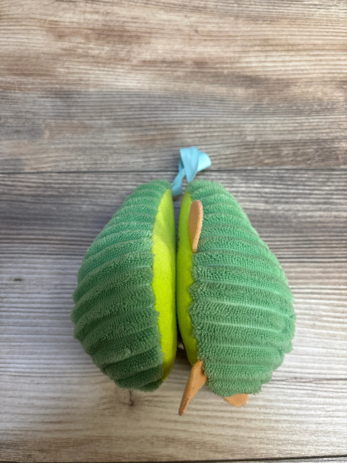 Green plush caterpillar toy with yellow belly and blue ribbon, perfect for baby playtime
