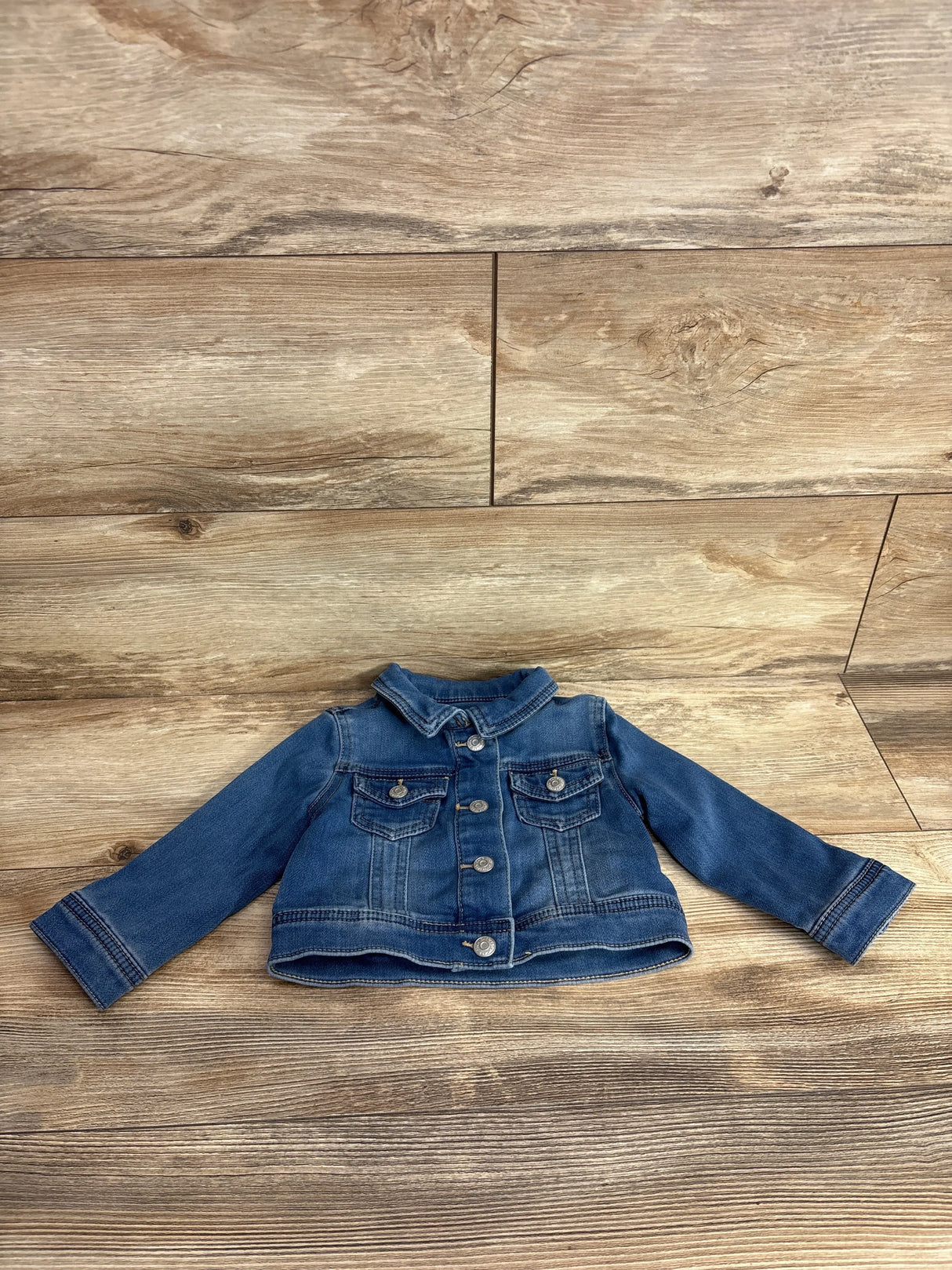 Kids denim jacket with long sleeves and button front on wood background