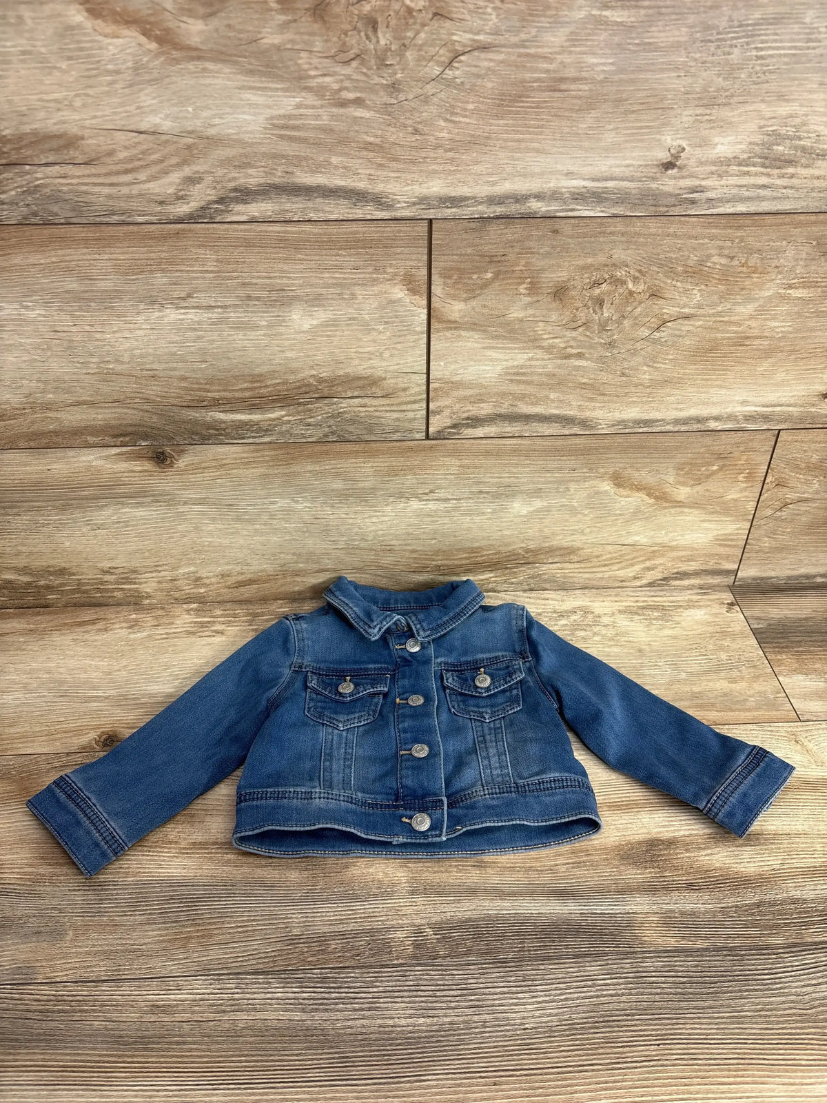 Kids denim jacket with long sleeves and button front on wood background