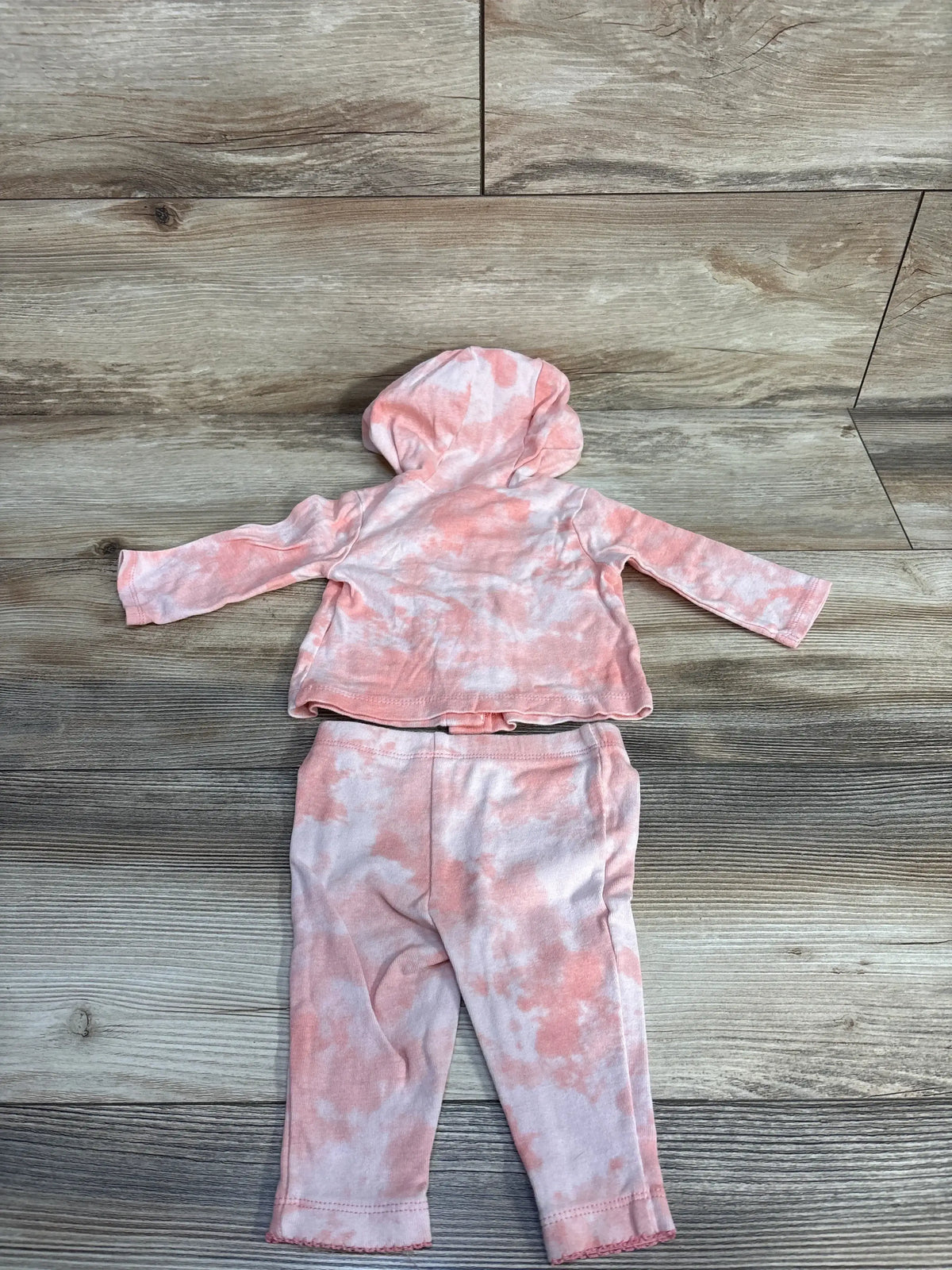 Pink and white tie-dye baby hoodie and pants set on wood background