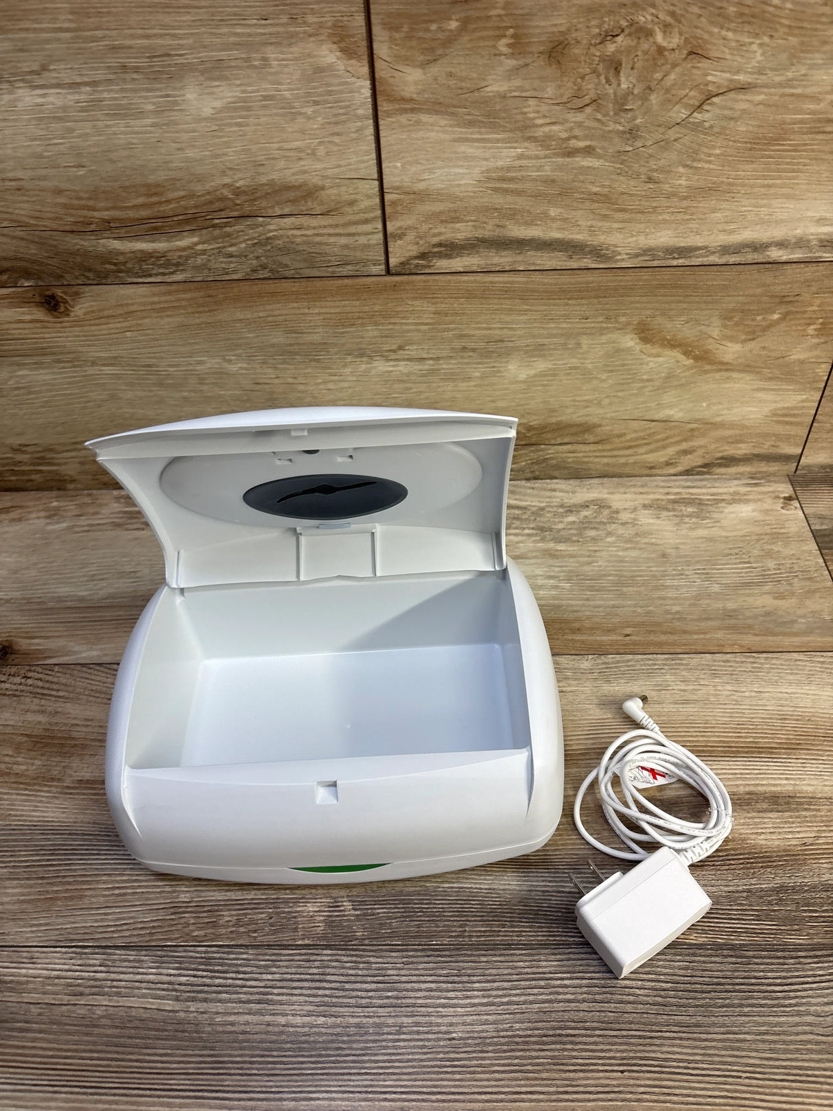 Front view of Prince Lionheart wipes warmer, lid open showing interior, power adapter included on wood surface