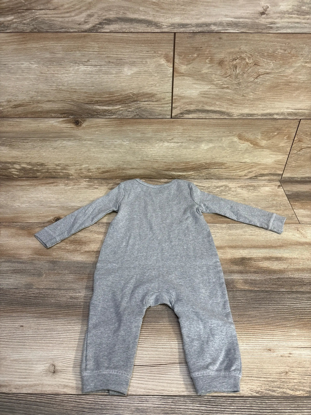 Top view of the Little Navy Little One grey coverall, size 6-9 months, with long sleeves and full-length legs on wood background